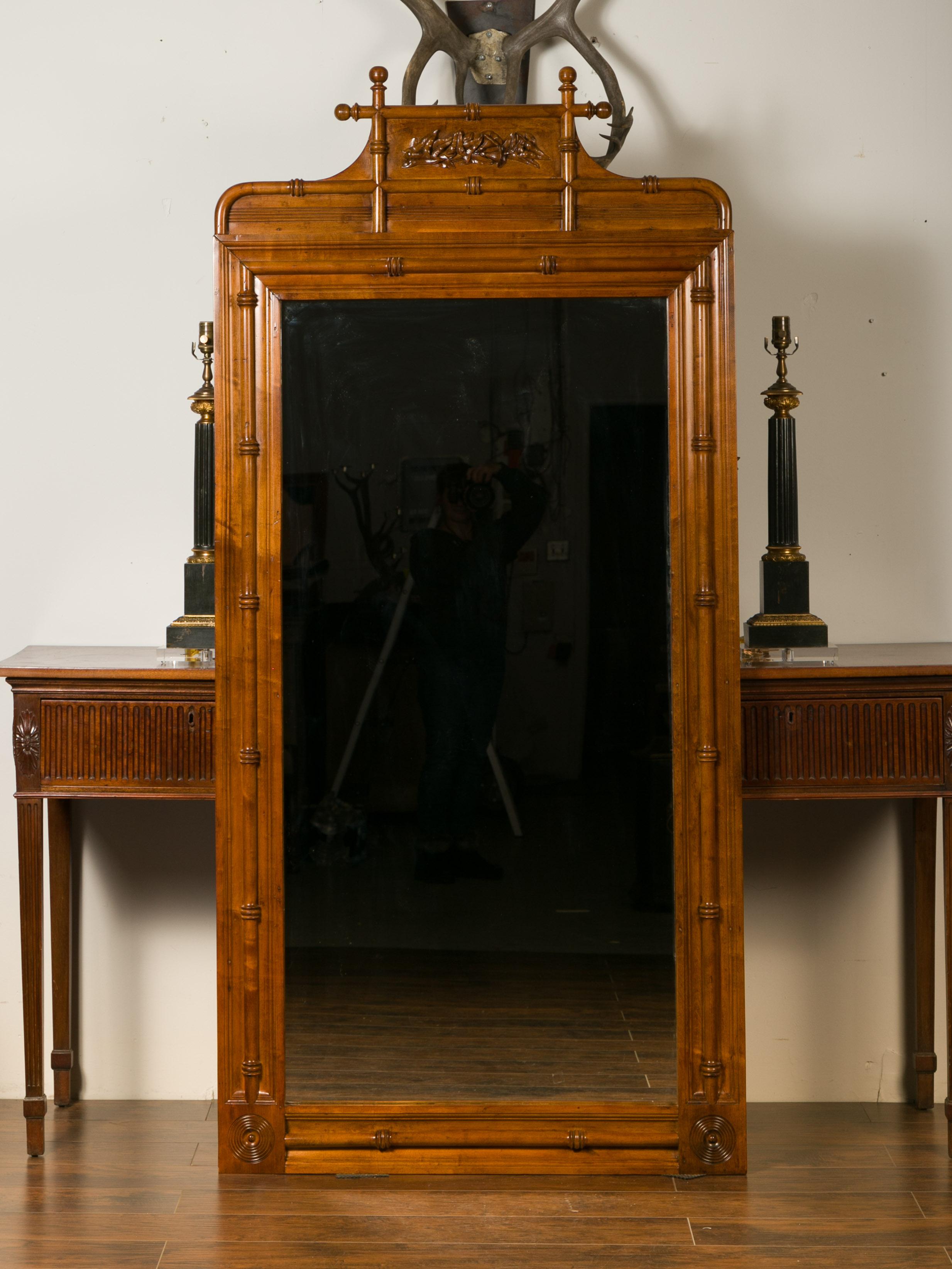 A large English faux-bamboo walnut mirror made from old doors from the early 20th century, with carved ivy motifs. Attracting our eyes with its tall silhouette and brown patina, this walnut mirror is made from old doors from the 1900s. The upper