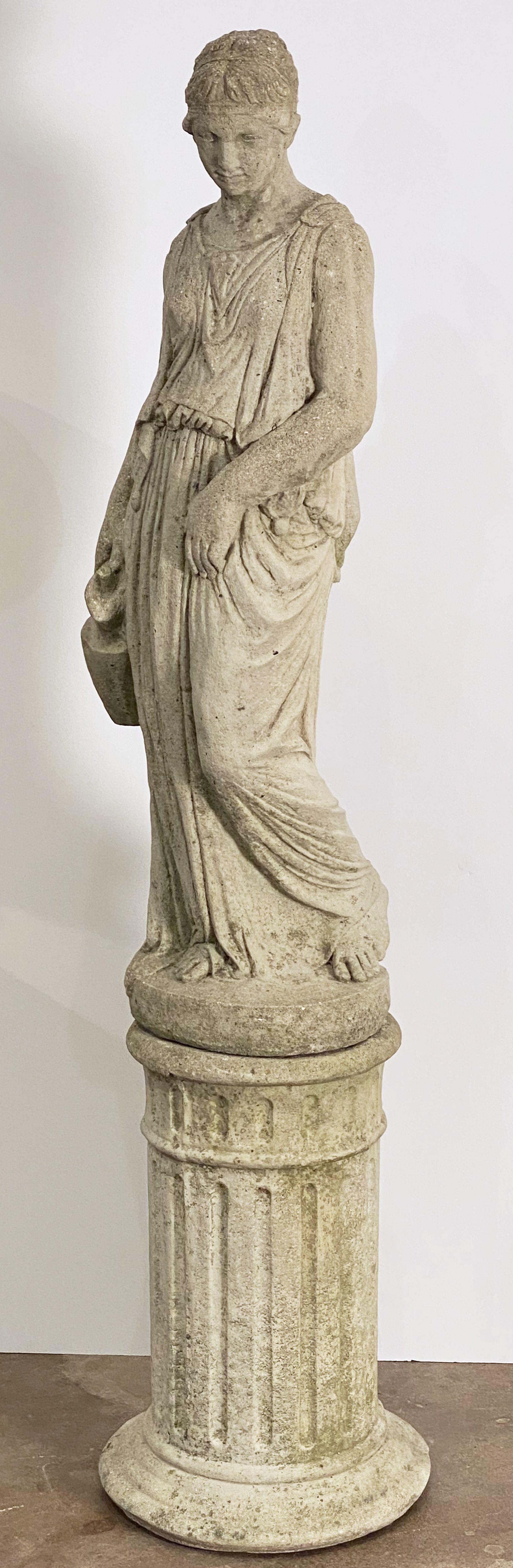 A large finely modeled English garden statue of the Classical maiden Hebe, of composition stone, featuring the goddess in a standing contrapposto pose 