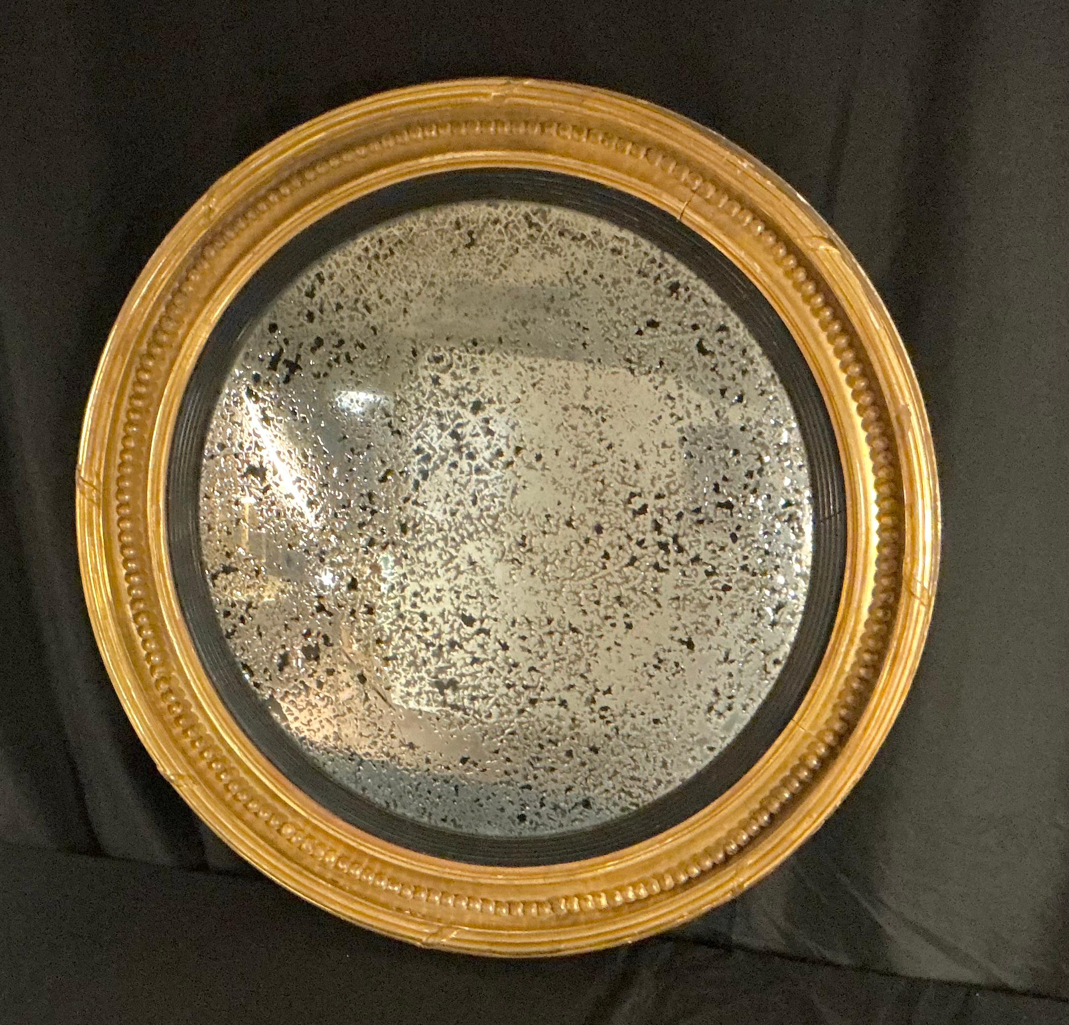 Miroir à œil de bœuf convexe en bois doré sculpté de style Régence anglaise du XIXe siècle, par Charles Nosotti. Le miroir est encadré de bois doré sculpté avec des détails perlés et un anneau intérieur ébonisé contrastant. La plaque de verre au