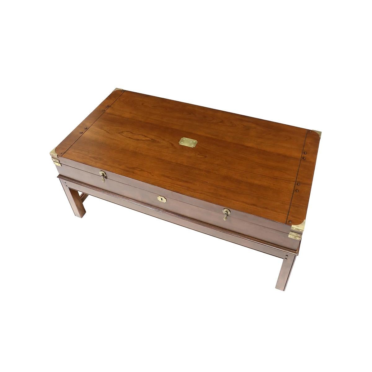 In the antique English Campaign style. The large lift-top wooden coffee table provides ample storage in a unique traditional style. With brass mounts and pulls. Raised on a Georgian style molded edge H form stretcher base. 

Dimensions: 48.75