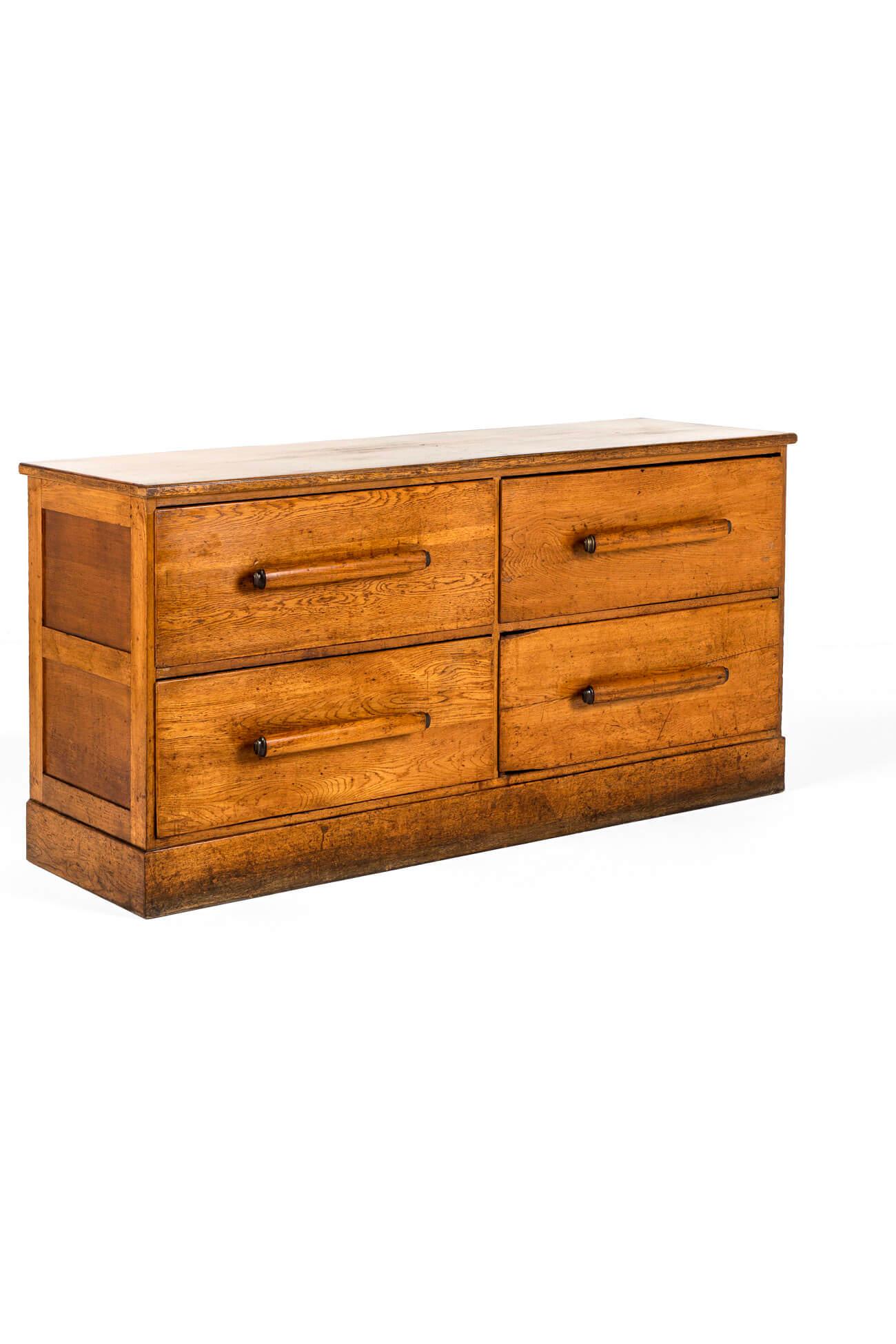 A substantial haberdashery cabinet with a set of four large smooth running drawers in oak and pine.

The deep drawers are complemented with thick original custom made turned handles with brass caps and fixing couplings to each.

The thick oak top