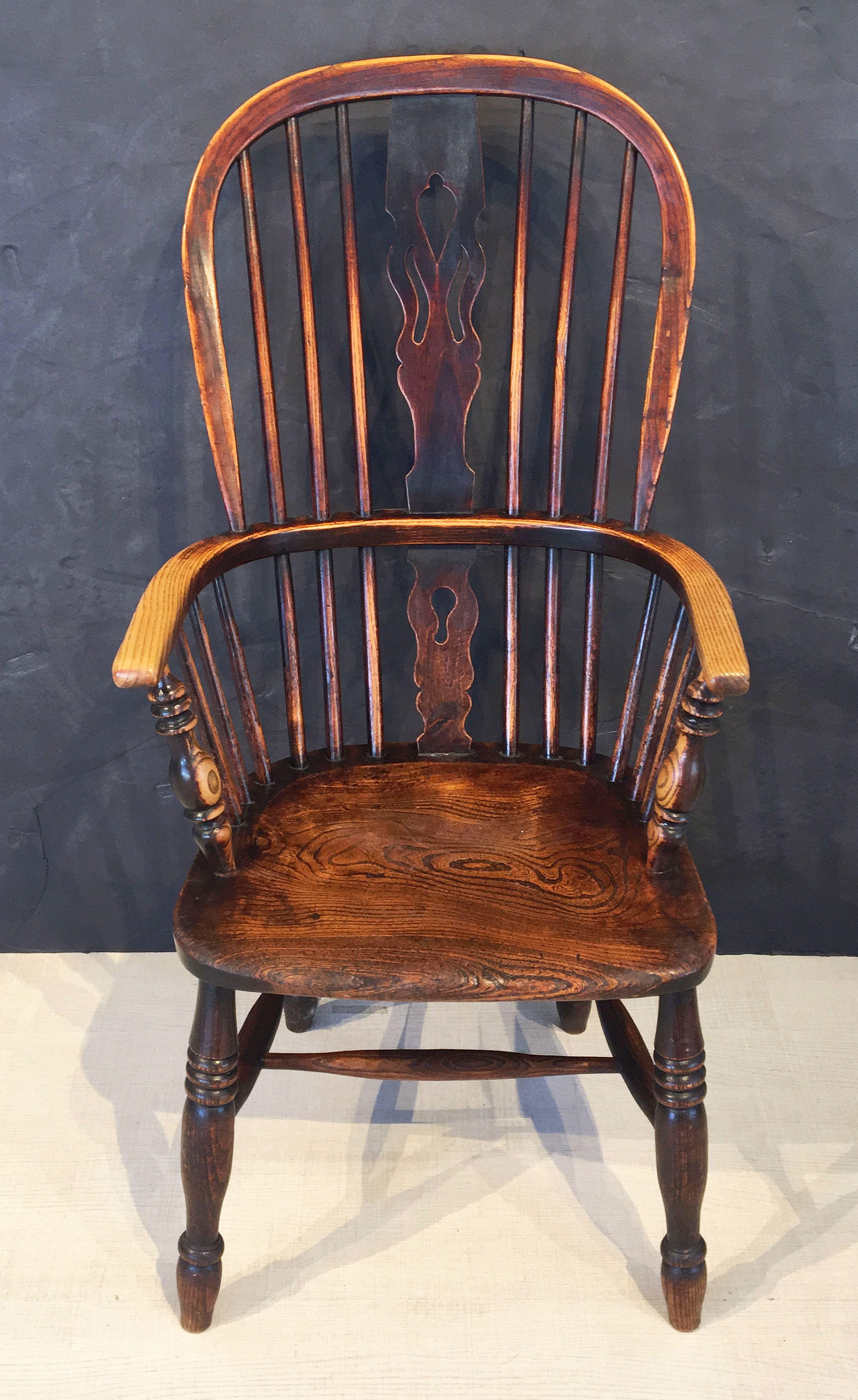 A handsome large English Windsor high back chair of elm and ash woods, featuring a bowed top rail and pierced splat and spindle back, with solid seat on turned stretcher.