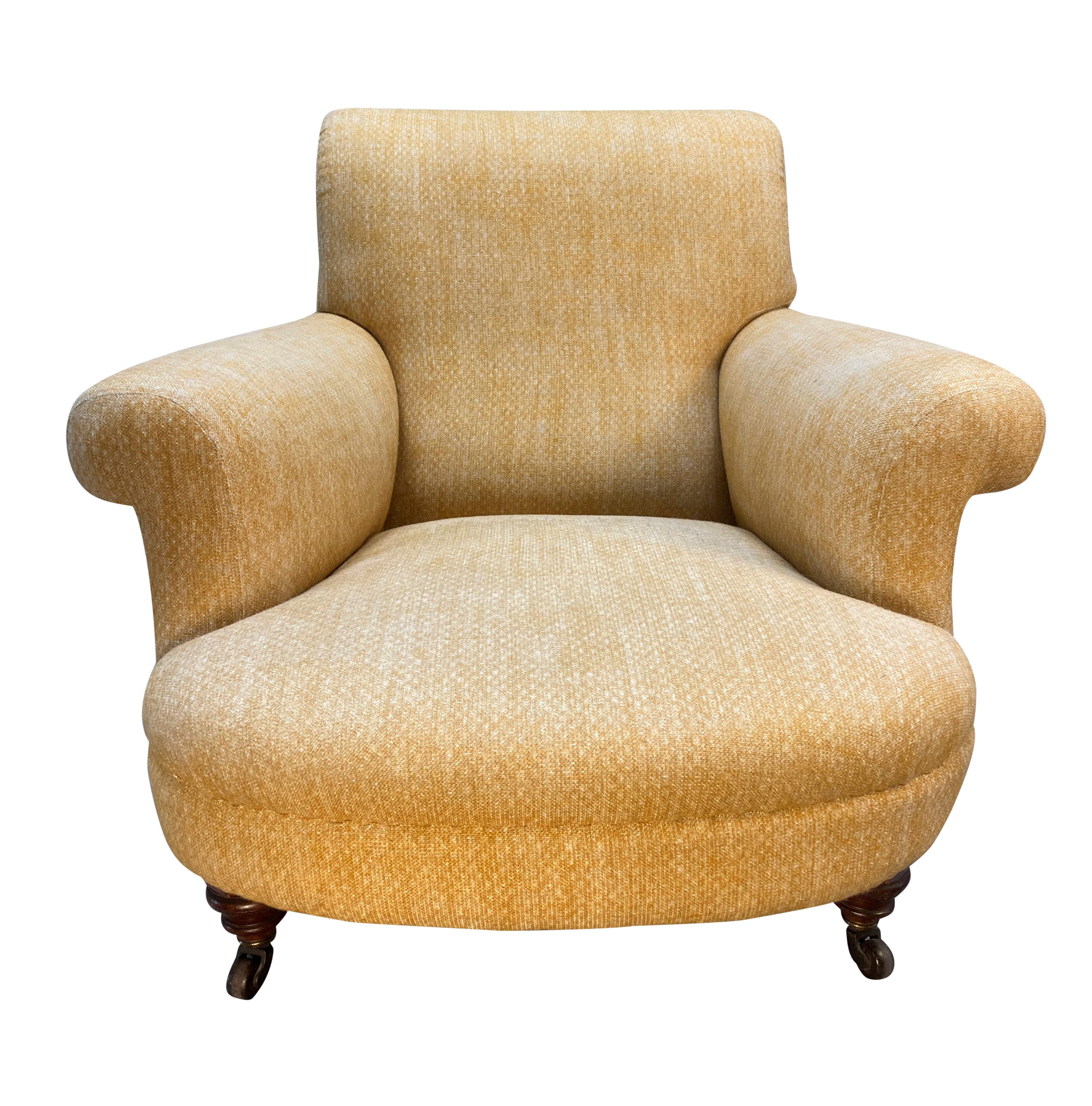 Un grand fauteuil club anglais de style Howard and Sons de grandes proportions, avec des pieds arrière évasés et des pieds avant tournés sur des roulettes en laiton. Le tissu de Fermoie est usagé mais en très bon état.