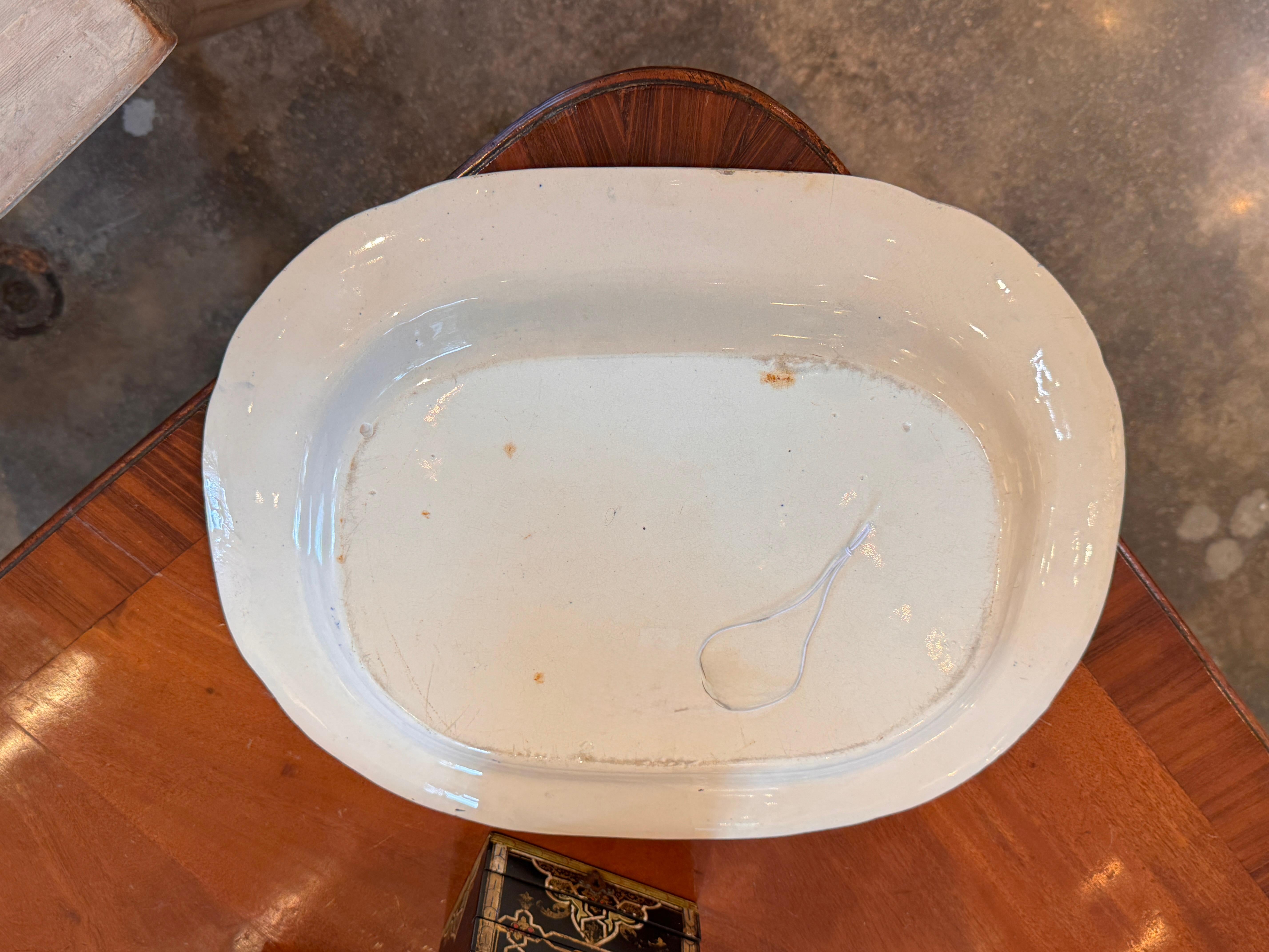 A generously scaled English ironstone serving platter featuring the classic blue and white willow pattern. The transferware design depicts an idyllic chinoiserie landscape, bordered by a geometric band and floral accents. Aged surface wear and faint