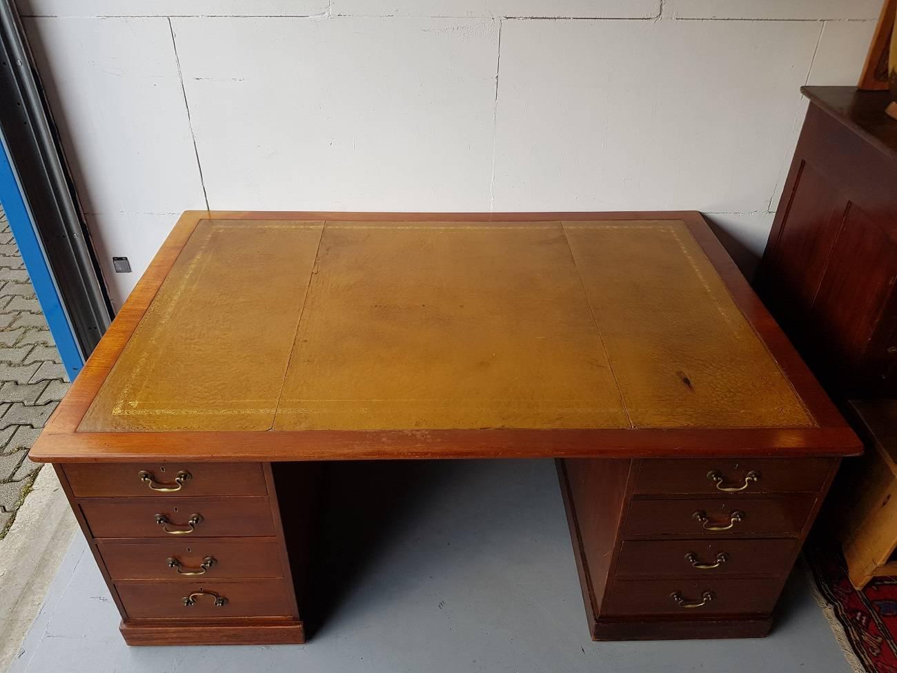 Large size English mahogany desk from circa 1900 with leather inlaid top and on each side four drawers on the other side two doors behind each one shelf, and there is so much space you can work with two people. It's in good but used condition what