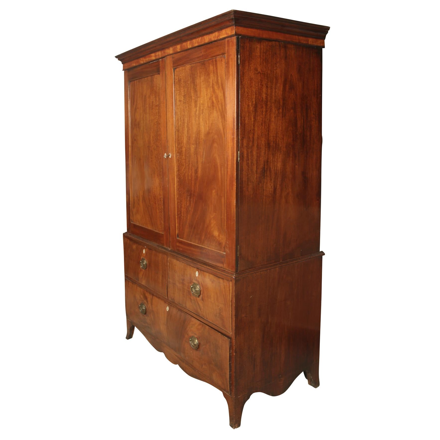 Large English mahogany linen press armoire, provenance Sotheby's. Two doors above with crown molding at top and three drawers below and scalloped apron below the drawers.