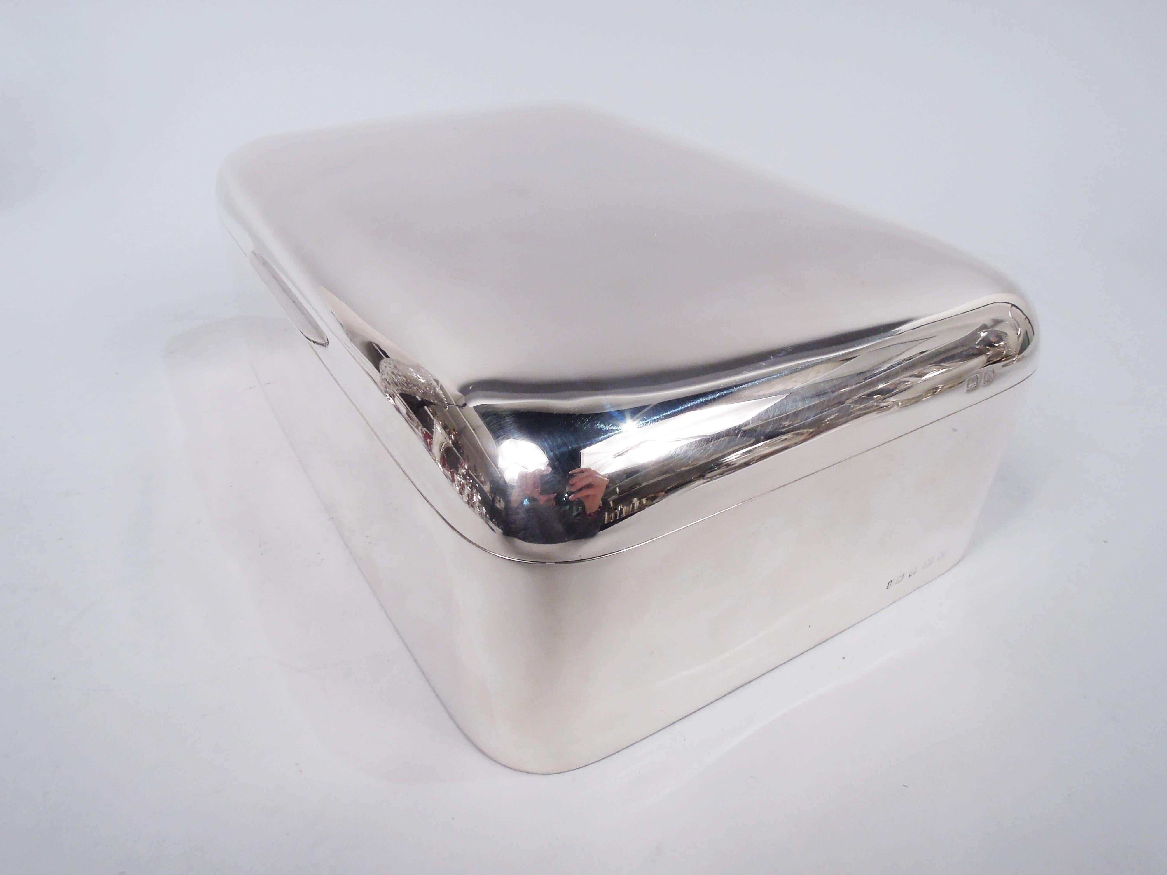 George V sterling silver box. Made by Henry Matthews in Birmingham in 1927. Rectangular with straight sides and curved corners. Cover hinged and tabbed. Box interior cedar-lined and partitioned. Cover interior gilt. Leather-lined bottom. Modern and