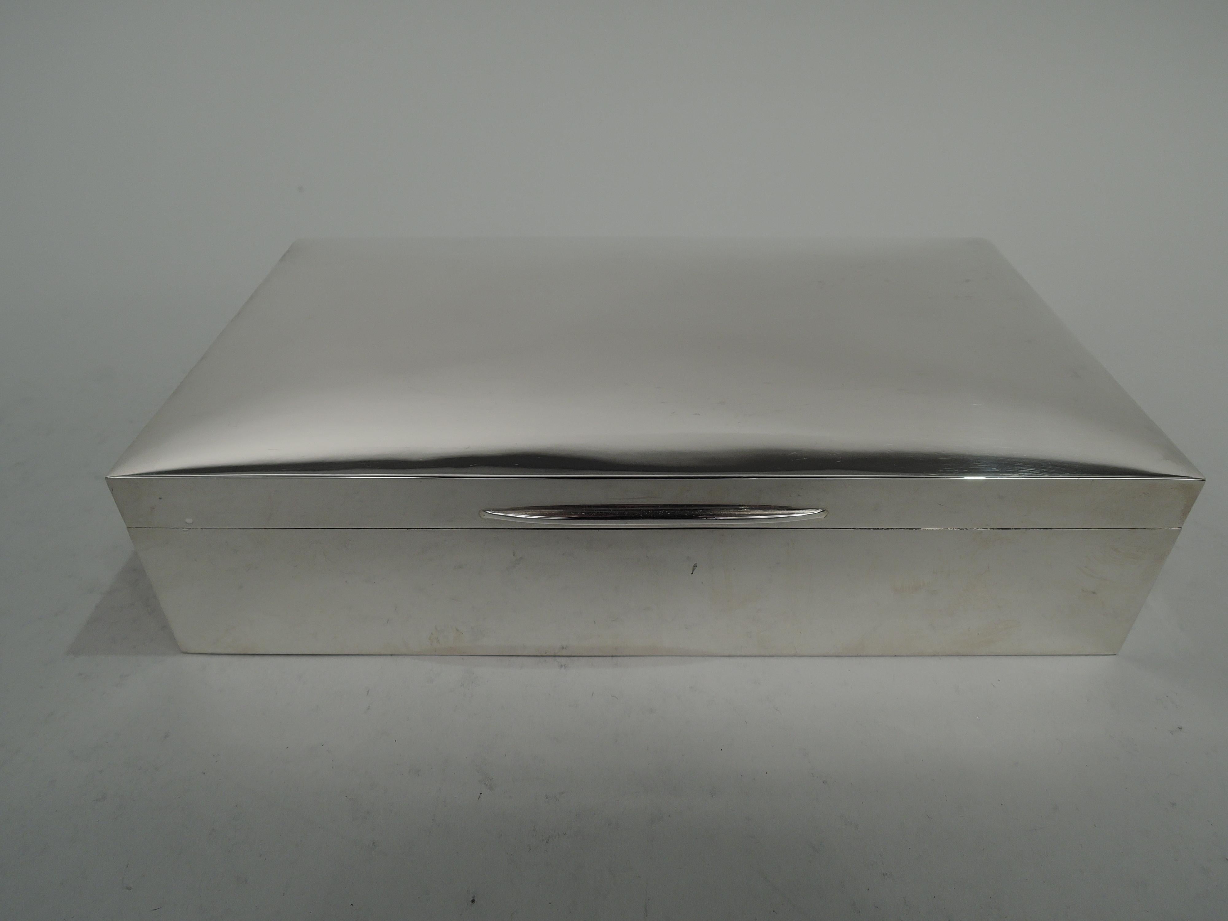 Elizabeth II sterling silver box. Made by Padgett & Braham Ltd in London in 1963. Rectangular with straight sides. Cover hinged with gently curved top and tapering tab. Interior cedar-lined and partitioned. Open leather-lined bottom. Heavy gross