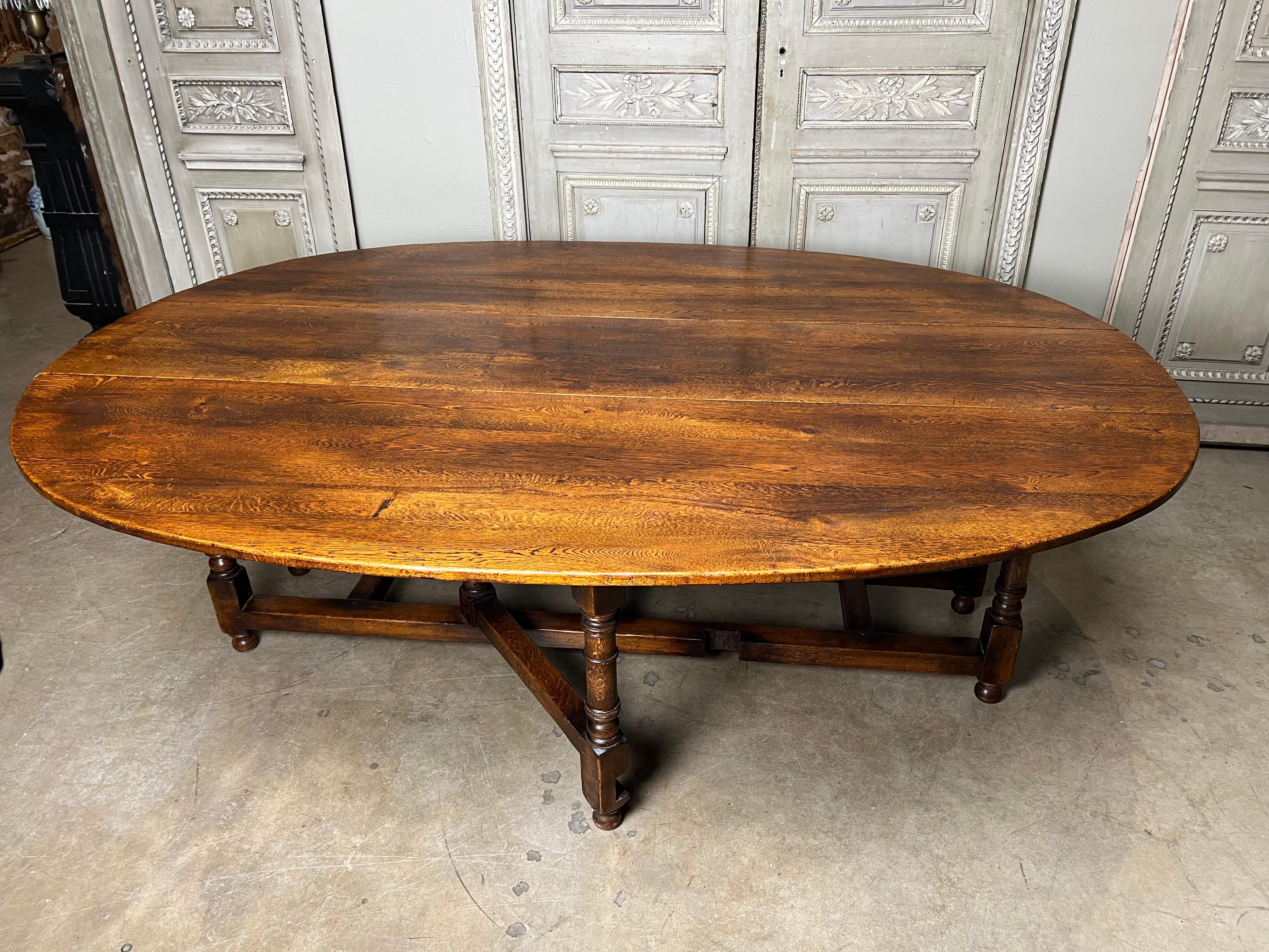 Une très grande table de salle à manger en chêne anglais à feuilles tombantes et à pieds en forme de porte.  Cette magnifique table peut accueillir confortablement huit à dix personnes et présente une forme ovale lorsqu'elle est ouverte.  
Elle peut