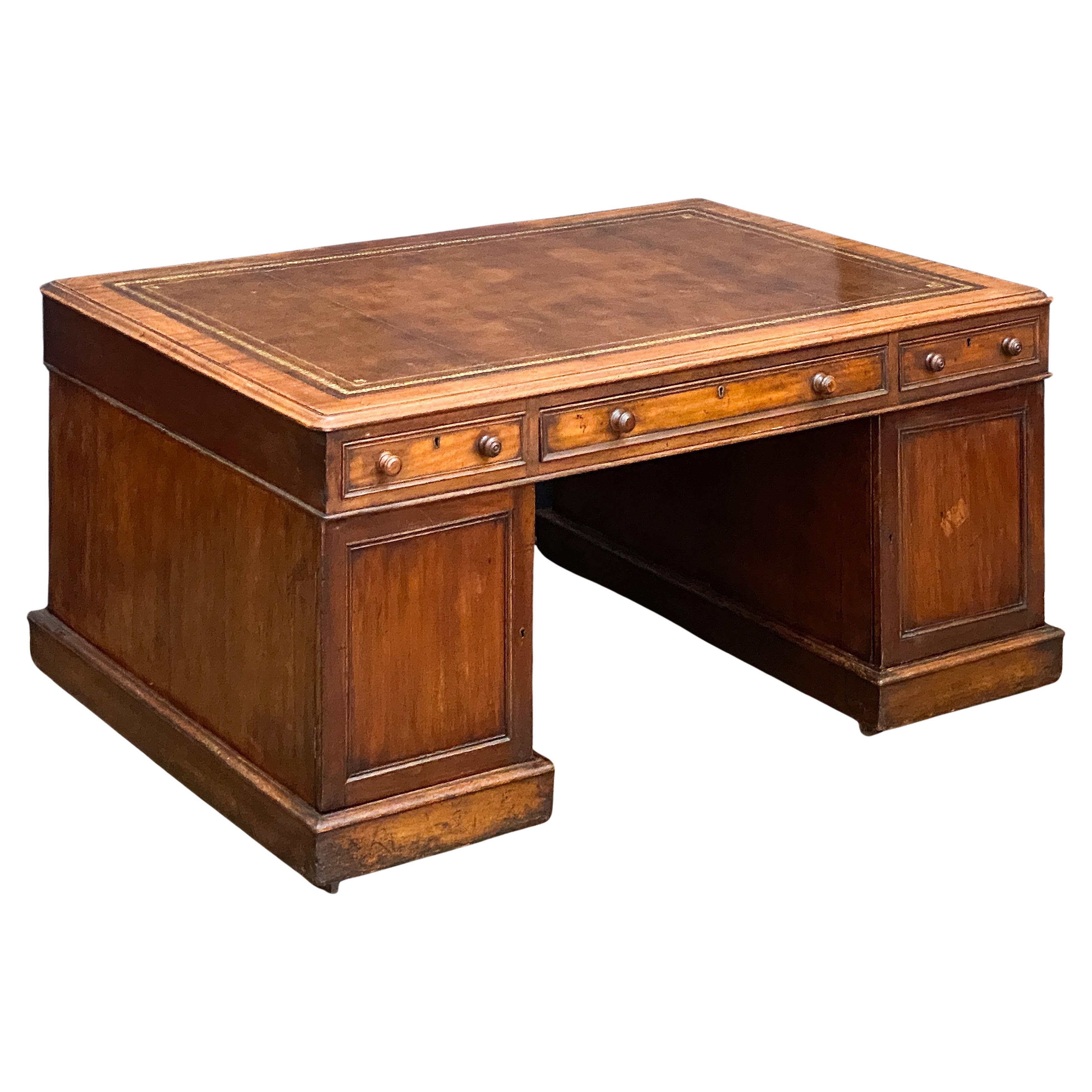 A large handsome English partner's double pedestal desk of mahogany, from the Edwardian era, featuring a moulded top inset with an embossed tan leather, over a frieze with one beaded long drawer flanked by two beaded short drawers on opposing