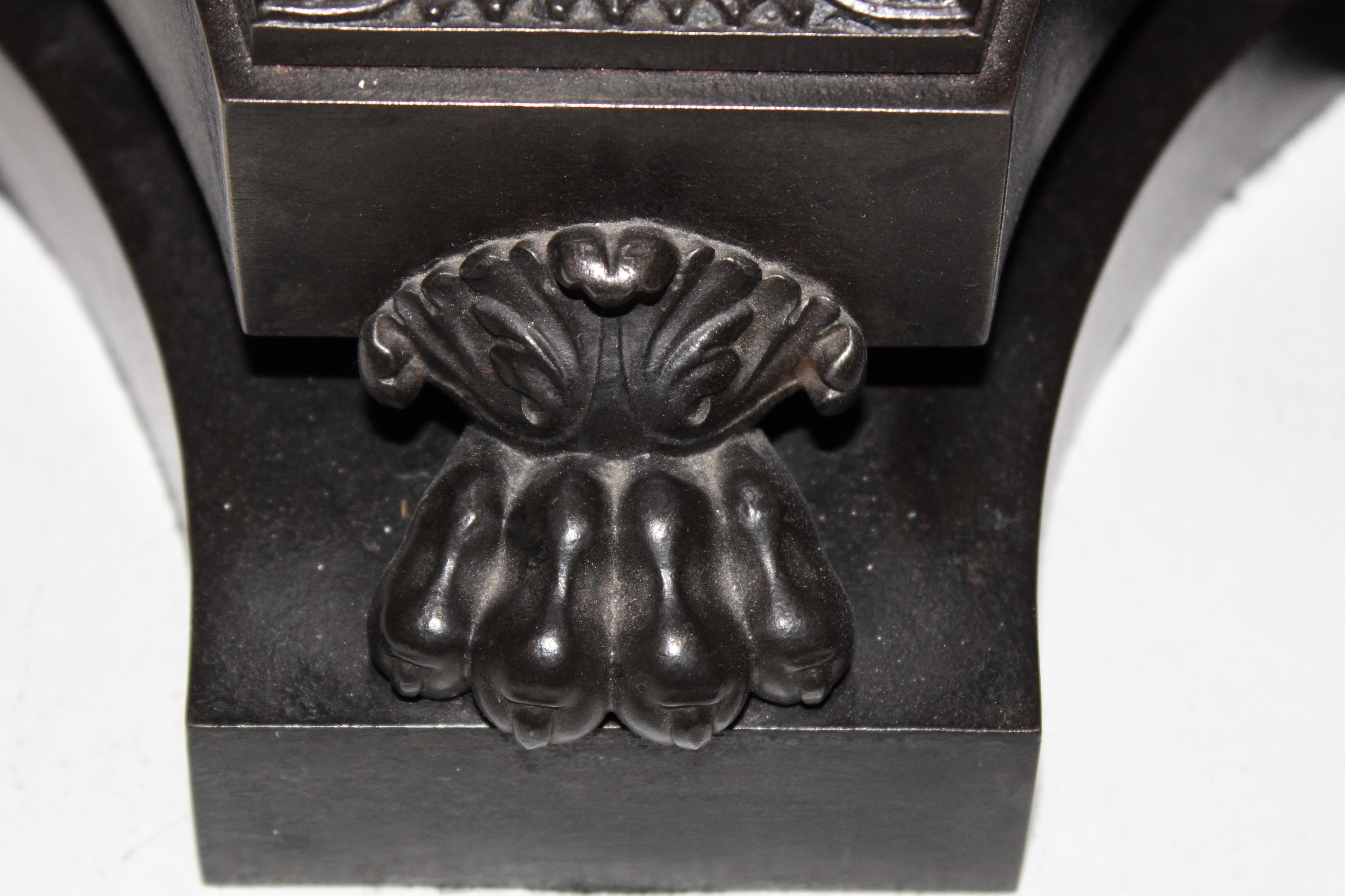 A large, finely cast English patinated iron neoclassical candle stand, circa 1860. The fluted column with four faces above ornate acanthus decoration and a triform plinth supported by paw feet.