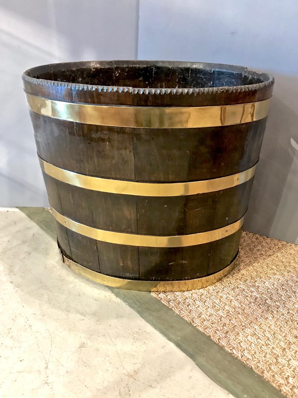 This is a very large English George III or Regency brass bound mahogany peat bucket. The bucket is in overall very good condition. The bucket features side open finger holds; tin liner is a replacement, but appropriate. The brass banding has
