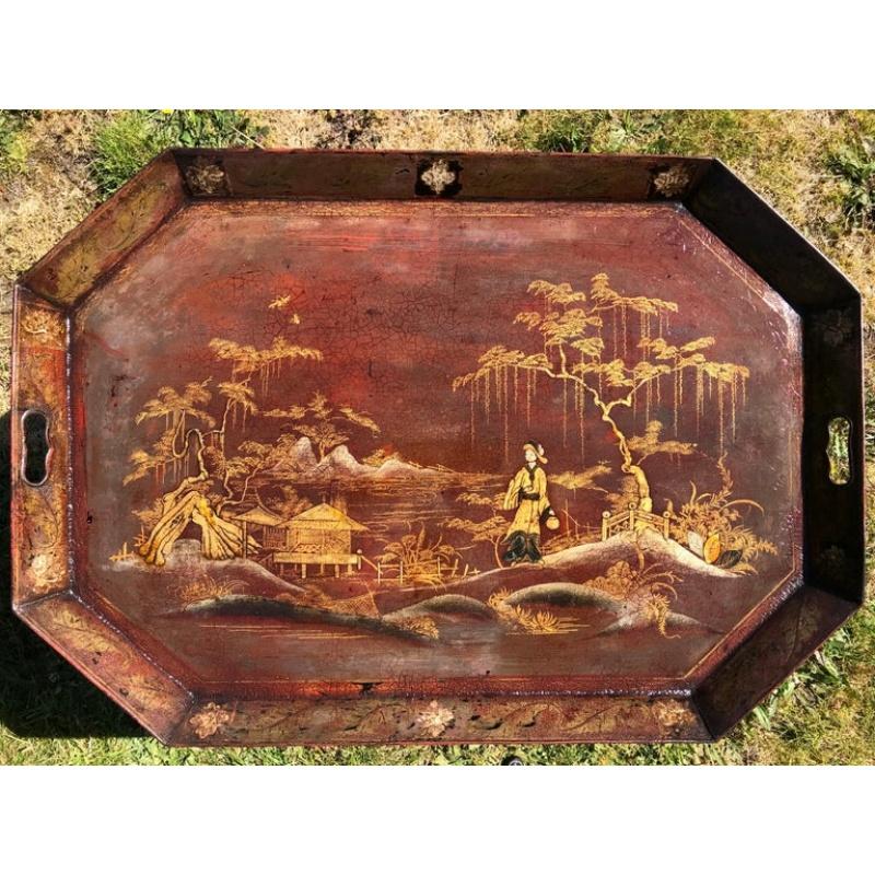 A large English chinoiserie japanned tôle (tole) tray table.
Regency period, early 19th century, circa 1810.

The gilt-heightened exotic landscape set on a Venetian-red ground. Depicting a watery seascape amongst pagodas, pavilions, rockwork, trees,