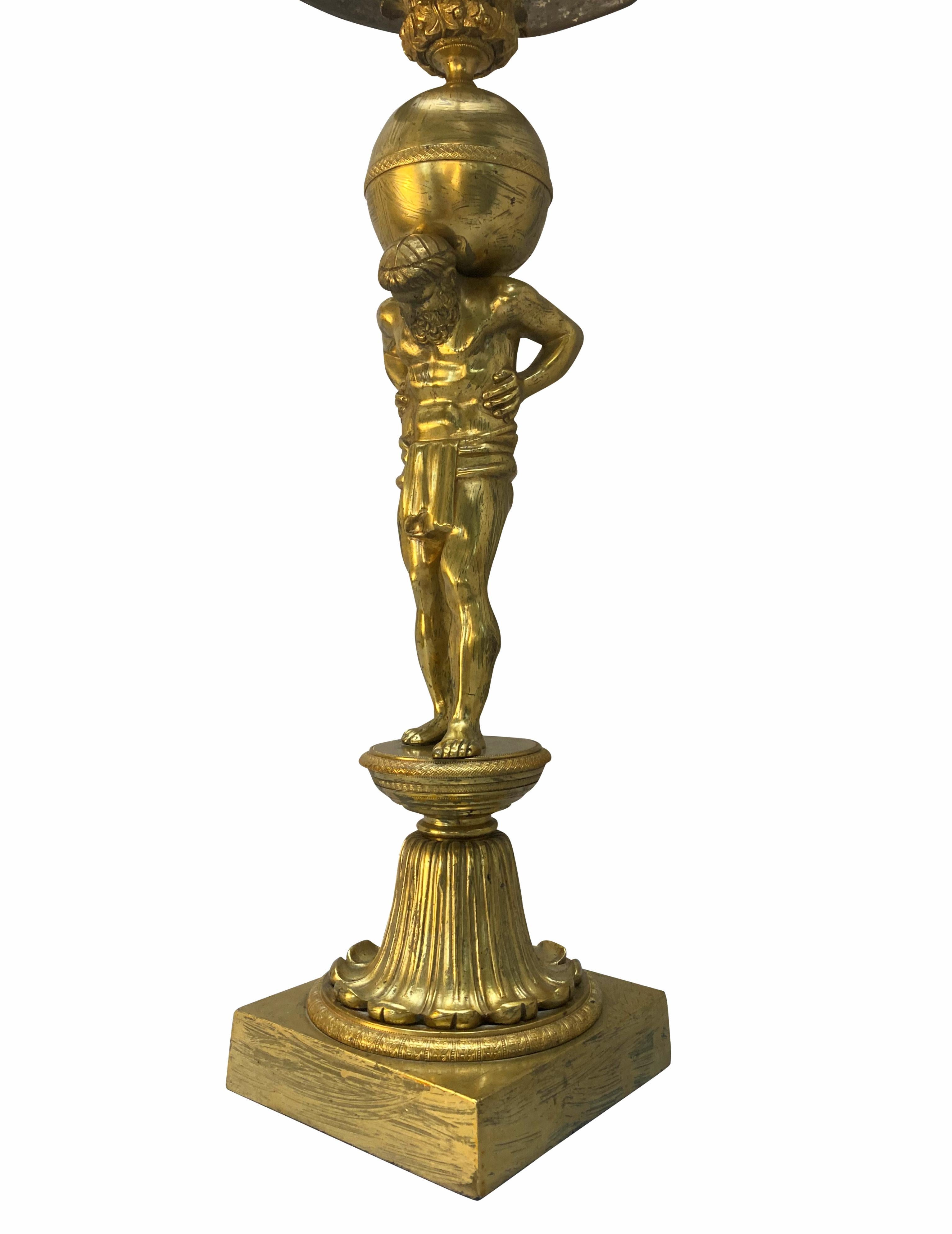 A fine XIX Century English gilt-bronze lamp depicting Atlas, holding up the earth, with a frosted glass shade. Formerly for oil, now electrified, and with good patina.