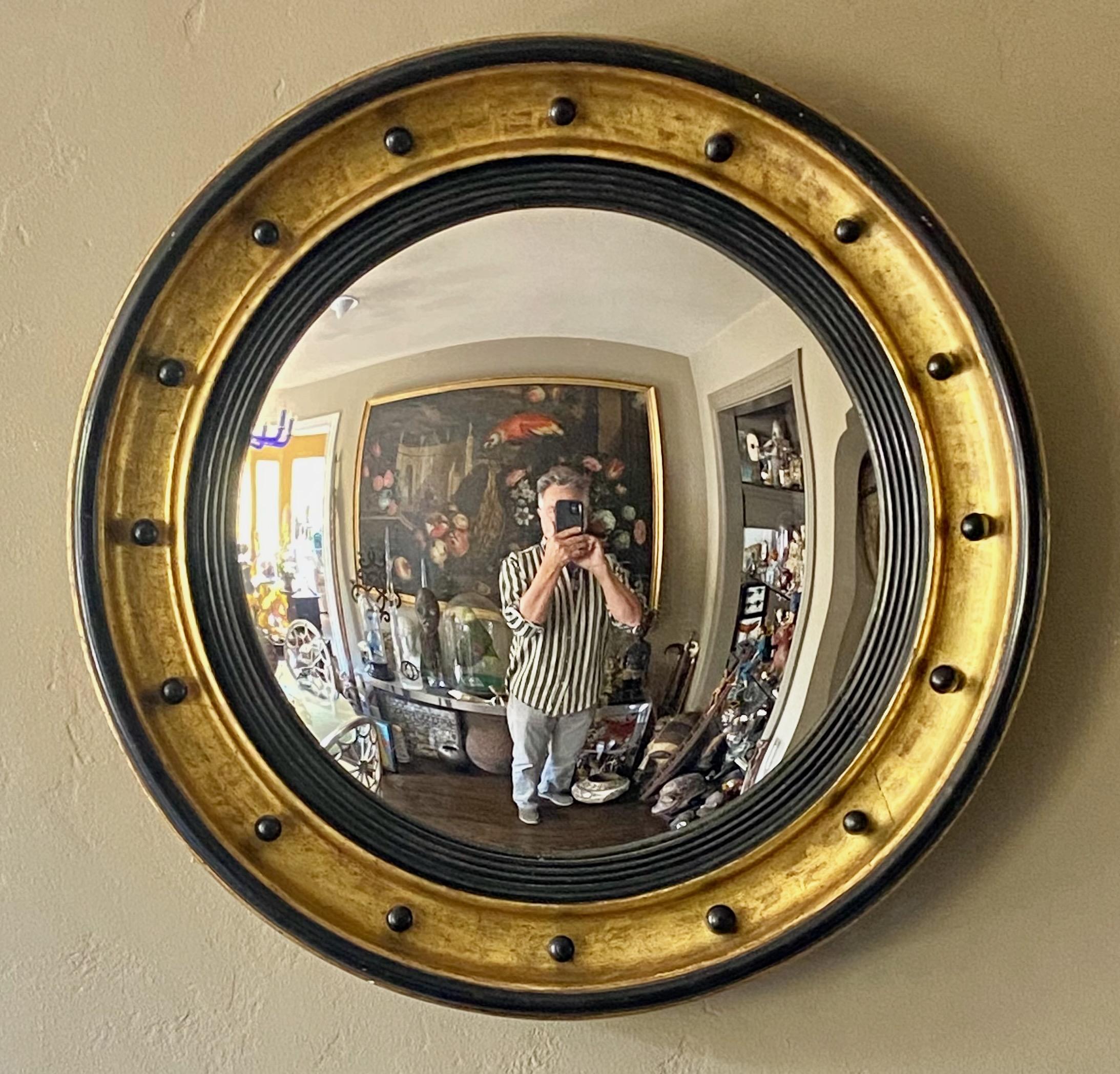 A large scale English Regency period gilt and lacquered convex mirror.
In remarkable antique condition. We believe this is completely original, 
having its original gilding, black lacquer and mirror.
England, Early 19th century.