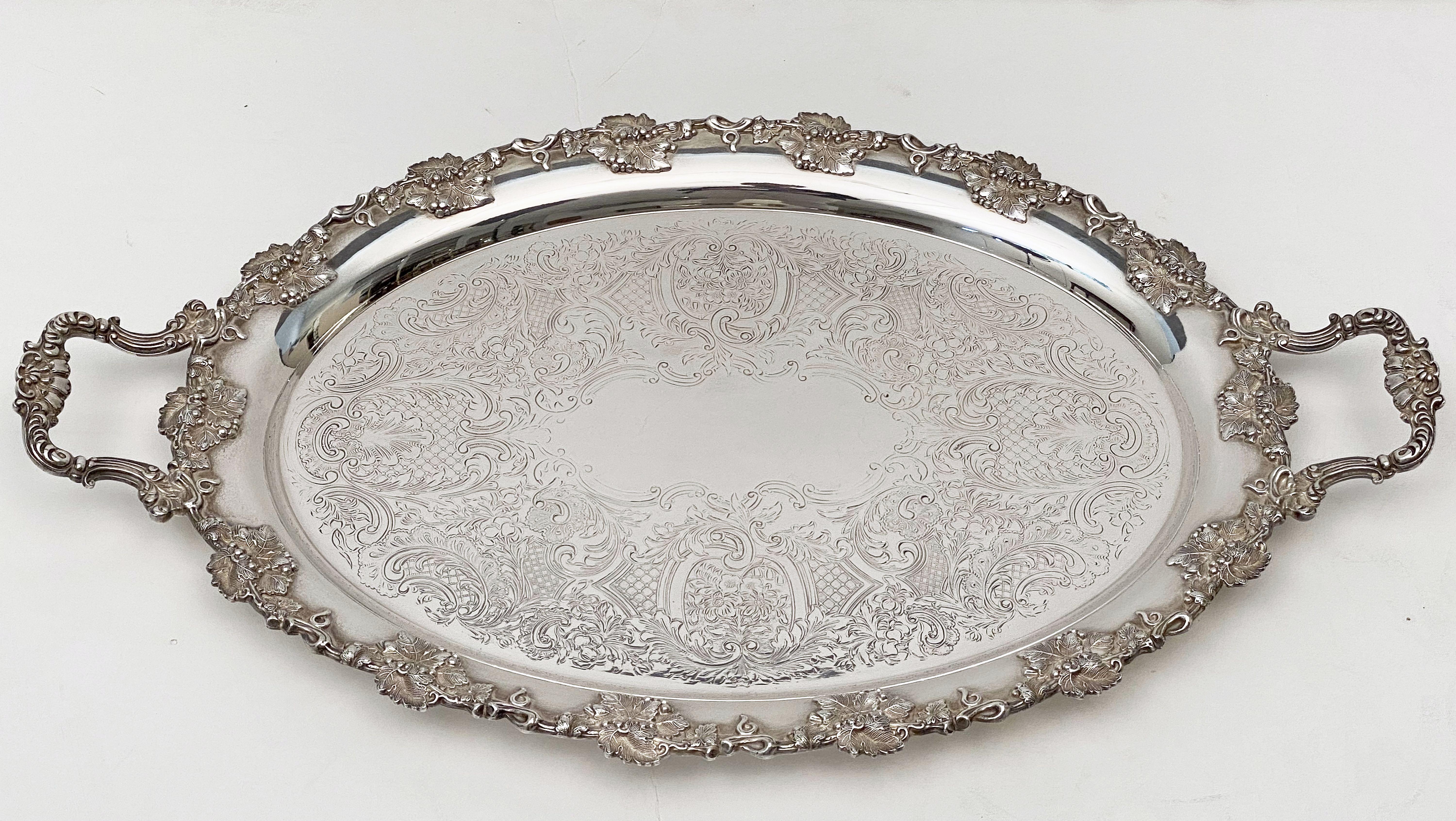 A handsome English oval serving or drinks tray of fine plate silver, featuring two opposing handles and a stylish pattern of grape clusters and leaves around the circumference, with an etched scrollwork design in the center.

Impressed mark on