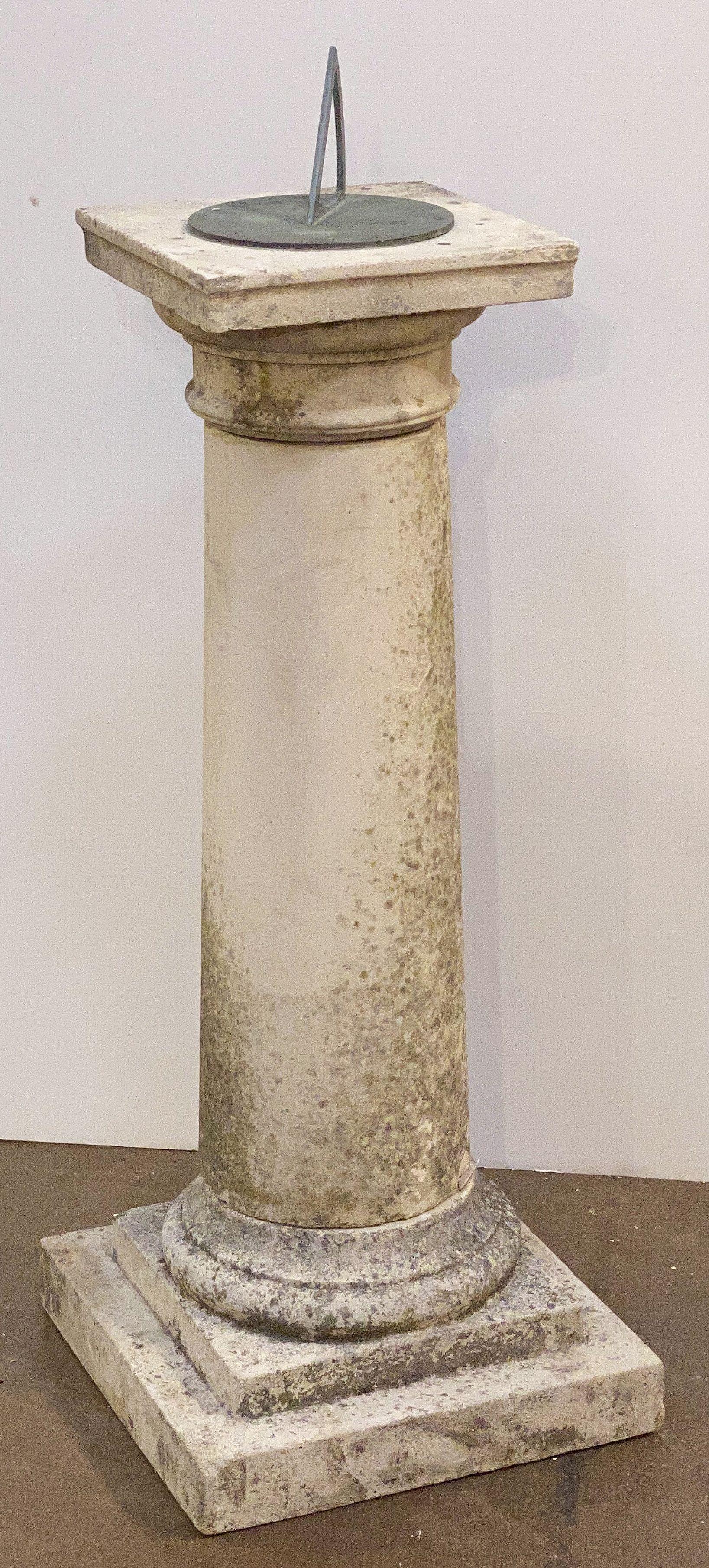 A large English sundial of composition or garden stone with a bronze dial and gnomon, featuring a bronze sundial inscribed with numerals, cardinal directions, and the Four Seasons of the year, along with a fixed gnomon (the shadow-casting object).