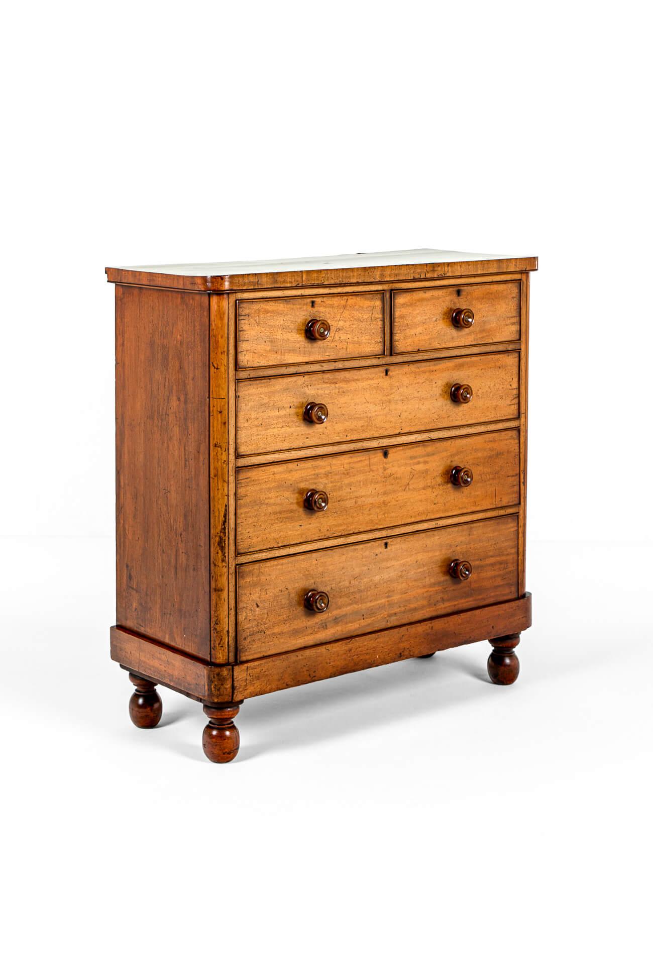 An imposing mid-Victorian mahogany chest of drawers with two short and three long cockbeaded drawers.

Each smooth running drawer has small brass escutcheons and turned mahogany button handles.

The bottom drawer is integrated seamlessly along the