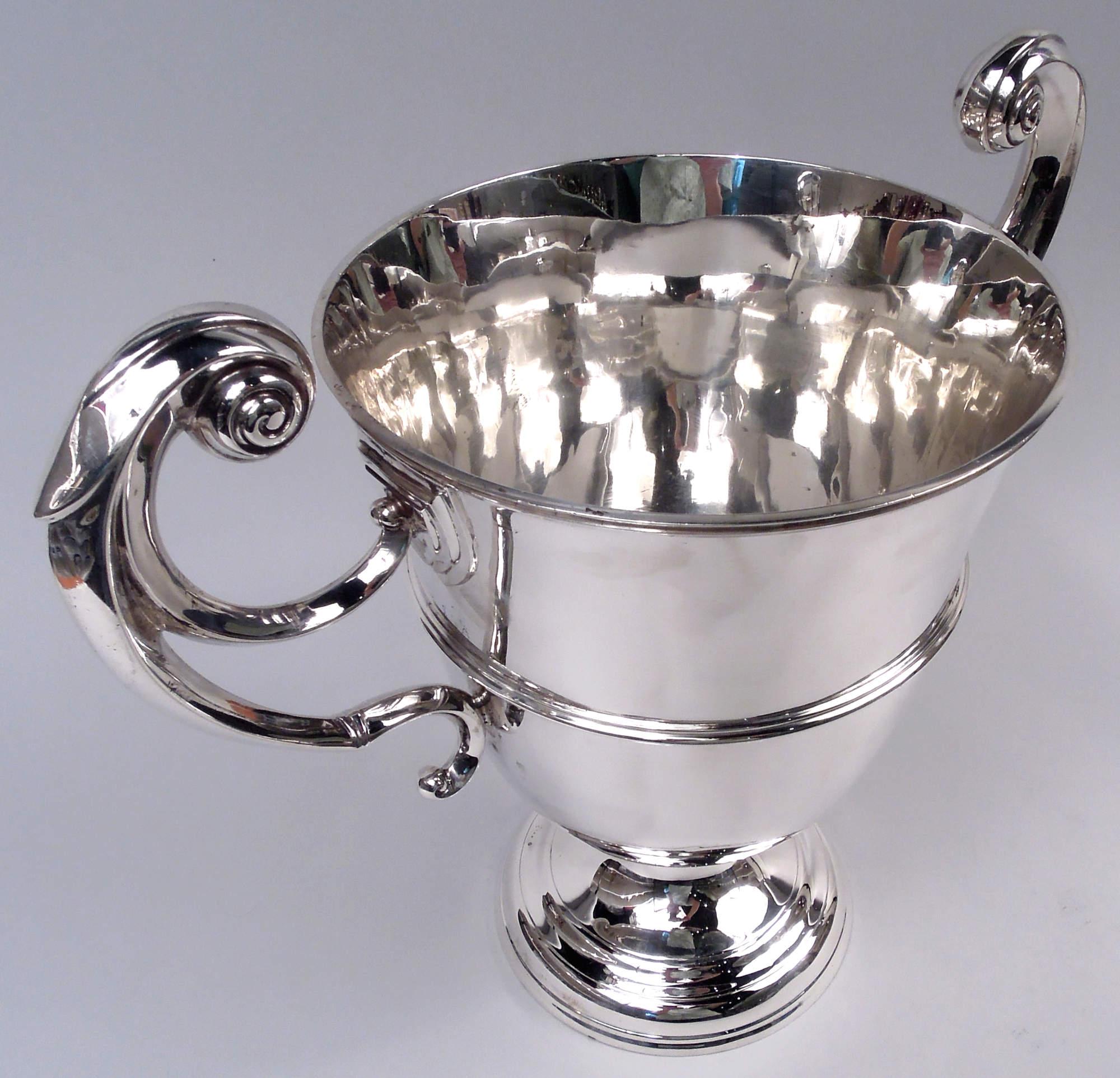 Coppa trofeo vittoriana in argento sterling. Realizzato da John Hunt a Londra nel 1897. Urna cinta con scudo e maniglie laterali a volute con cappuccio a foglie; piede a cupola. Forma tradizionale neoclassica. Spazio sufficiente per incidere un paio