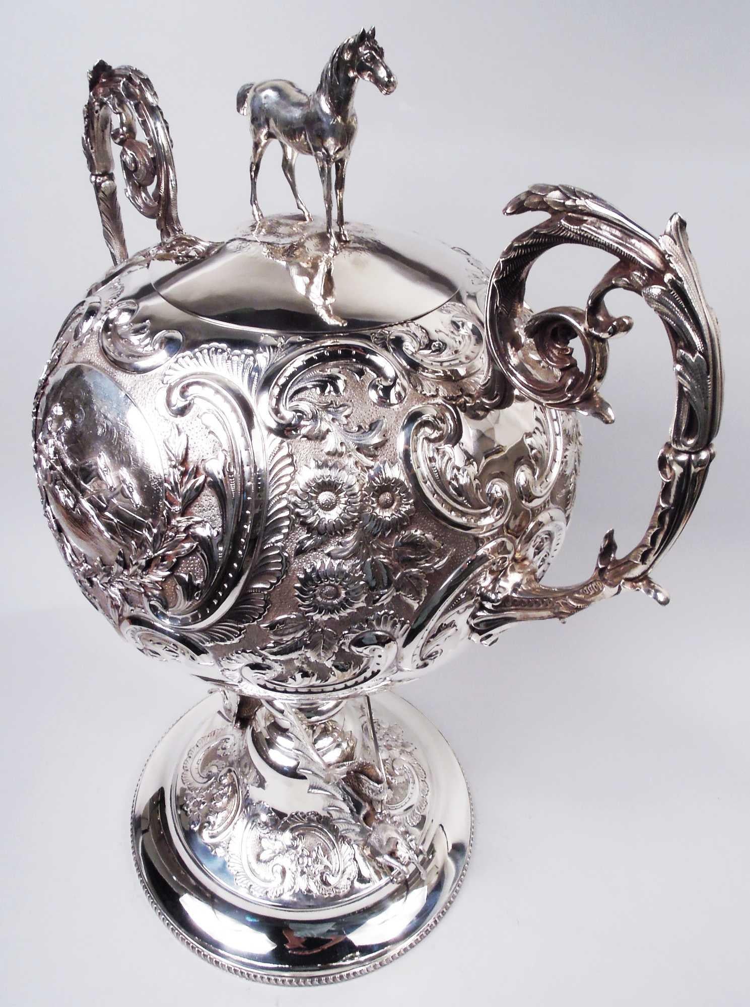 Large Victorian sterling silver trophy awarded for harness racing. Made by Barker Brothers in Birmingham in 1898.Gobular bowl with cast horse cover finial. Leaf-capped and -wrapped scroll handles. Knopped support on raised foot with two cast