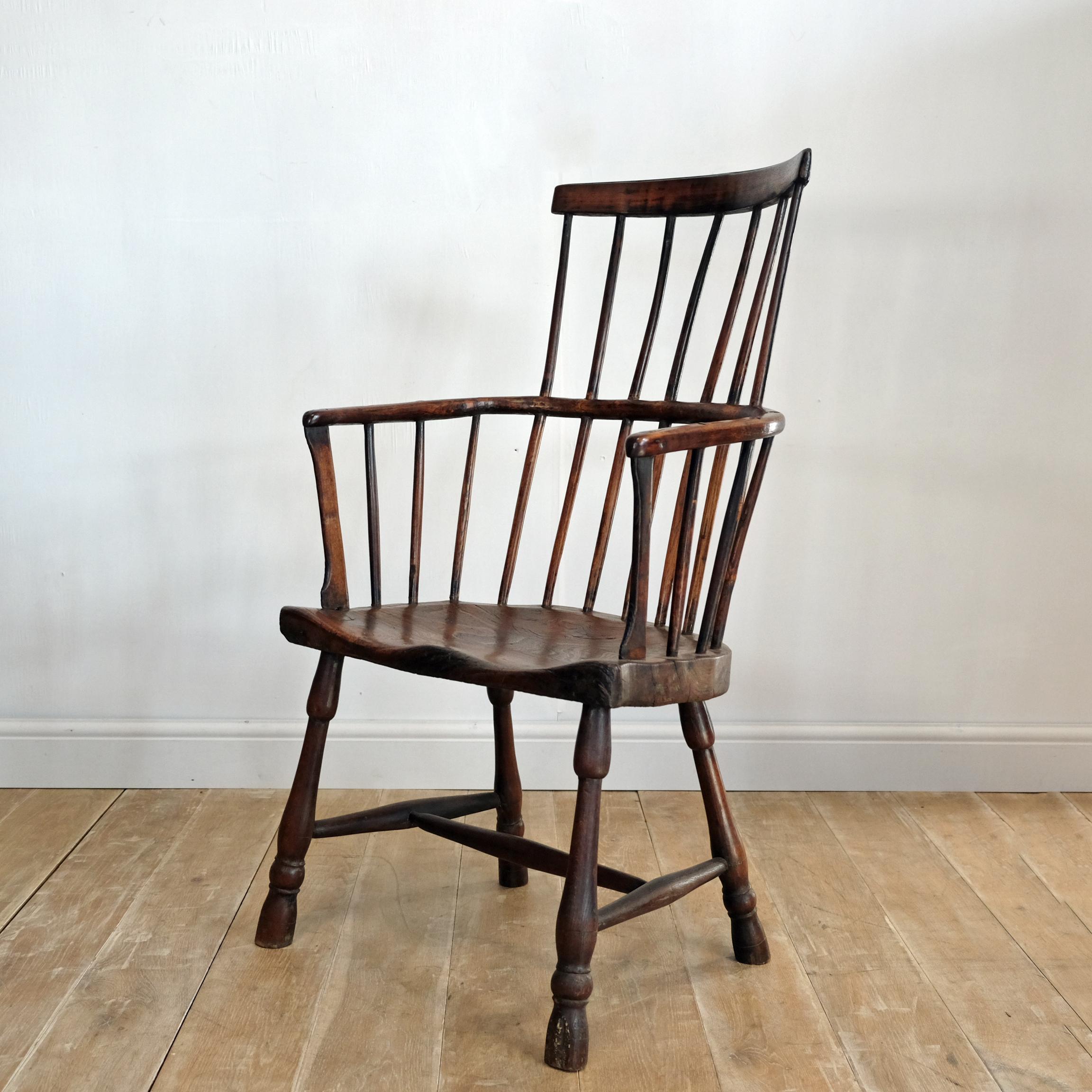 An exceptional large 18th century West Country comb back Windsor chair with thick shaped elm slab seat supported by four egg and reel turned legs, united by a tapered H stretcher. Flattened arm supports and simple hand drawn spindles with single