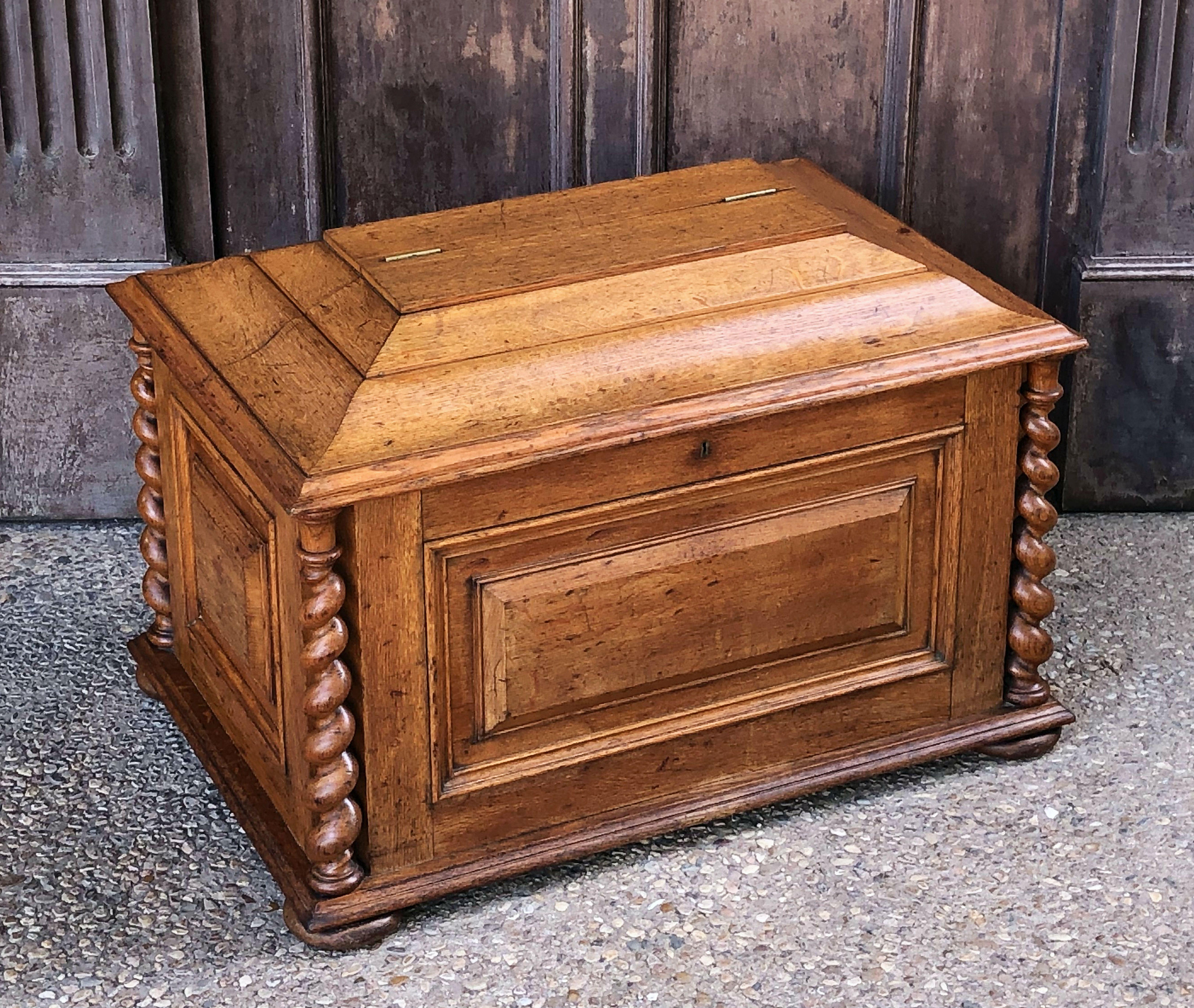 A fine large English cellaret or wine cooler compendium of patinated oak from the mid-19th century, featuring a classical sarcophagus with a hinged lid and a fitted interior with room for plenty of bottles. The exterior with turned barley twists on