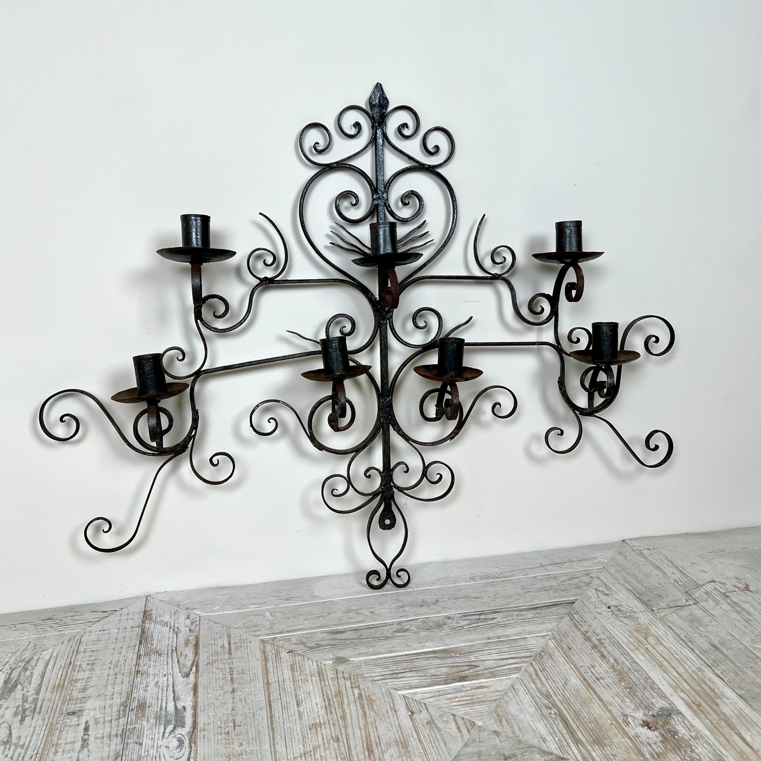 Gran candelabro de pared de hierro forjado inglés en forma de corazón - Portavelas forjado a mano

Aplique de pared de bella factura, fabricado en herrería, con una cresta en forma de punta de flecha sobre un elegante corazón de volutas. A cada