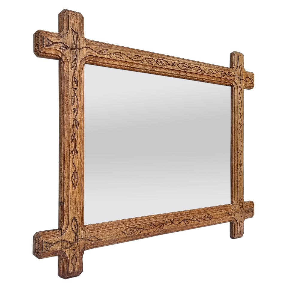 Seltener französischer Spiegel aus heller Eiche mit einer originellen Form, die mit eingravierten Blättern im Folk-Art-Stil verziert ist. Rahmenbreite: 7,5 cm - 2,95 Zoll. Moderner Glasspiegel. Rückseite aus antikem Holz.