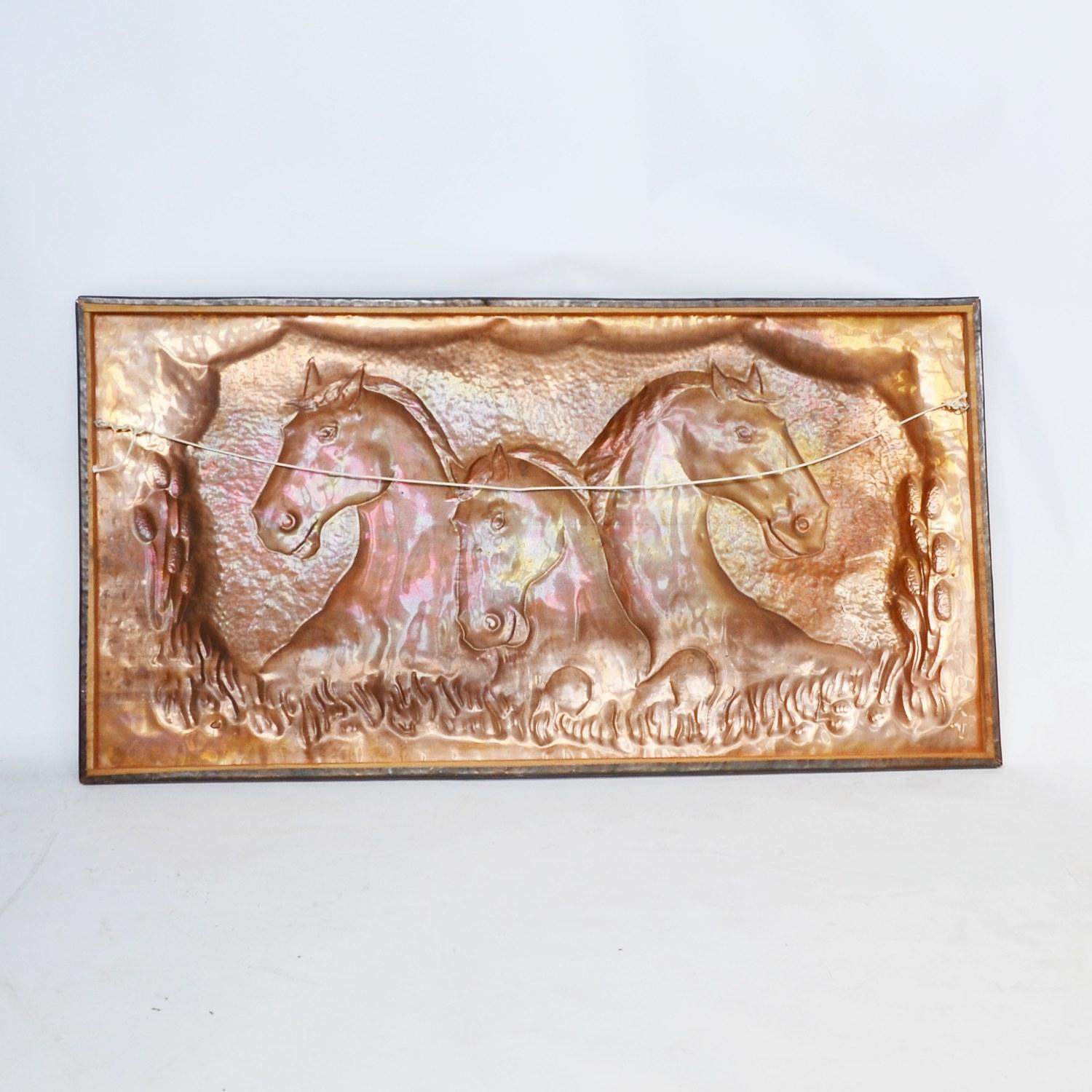 A large equestrian embossed copper plaque. Rectangular plaque with the heads of three rearing horses, surrounded by meadow detail. 

Dimensions: H 55cm, W 107cm, D 2cm

Origin: English

Date: Contemporary

Item number: 2409208.