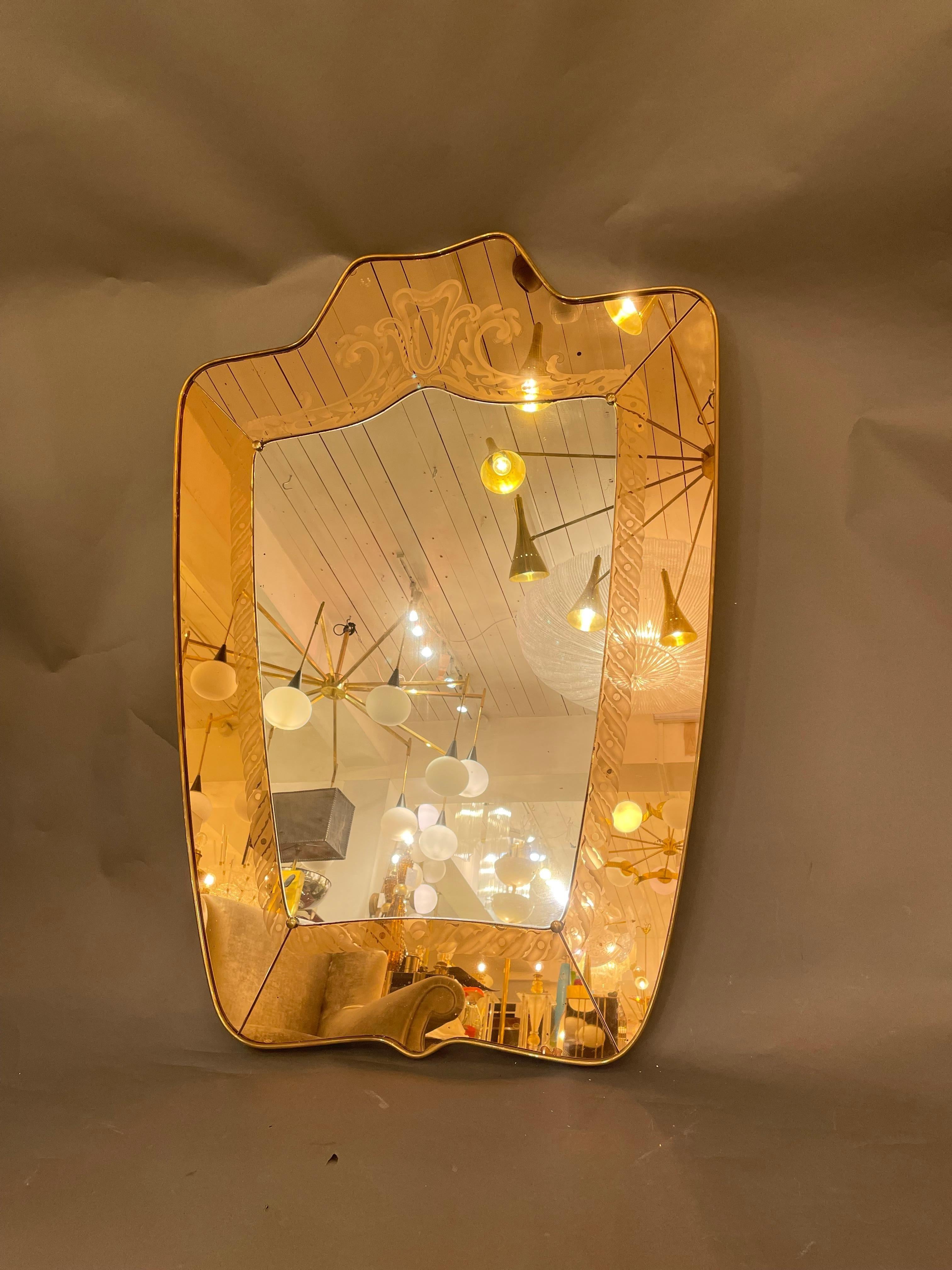 A etched pink glass mirror with brass frame designed by Pietro Cheese for Fontana Arte, circa 1940.