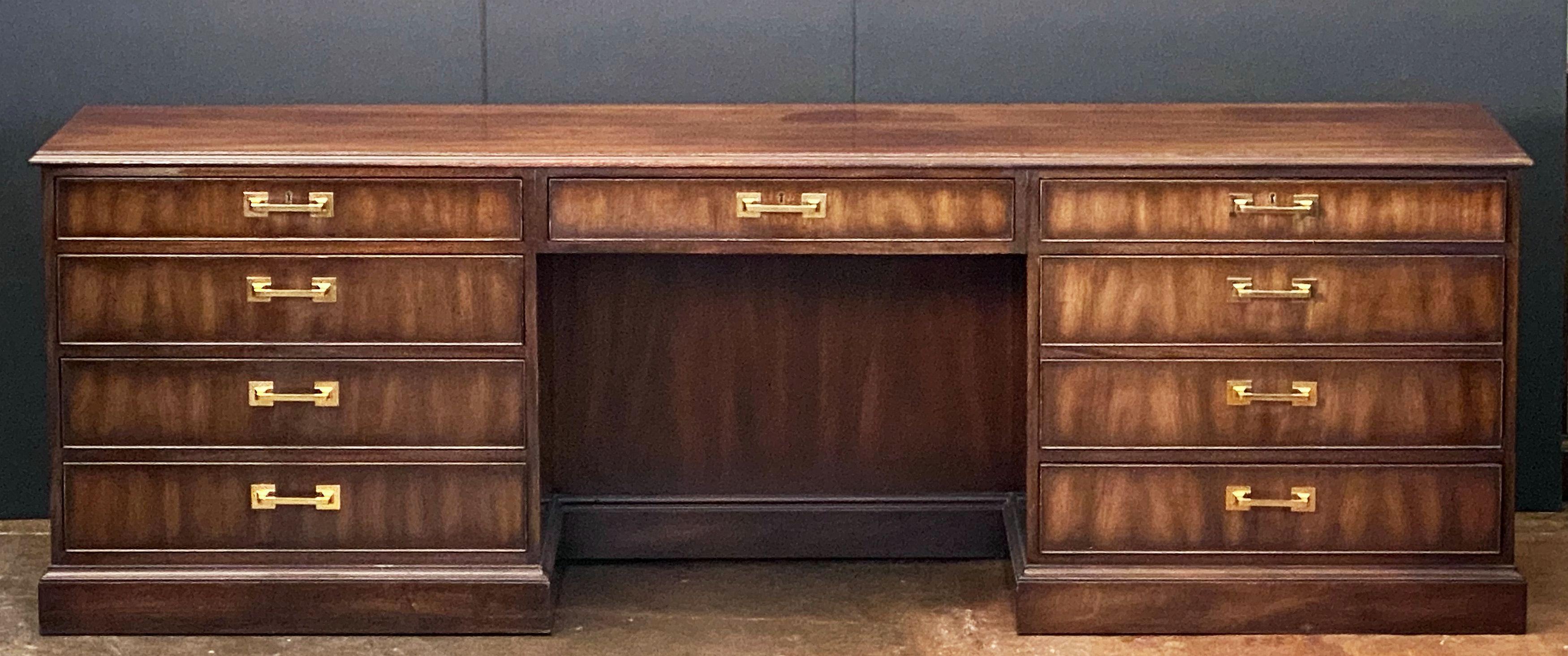 A fine large executive console table or storage cabinet, featuring a moulded wood top over a frieze of drawers and one cabinet drawer for files, in a pedestal style with kneehole center, by Kittinger.
With metal Kittinger name plaque in