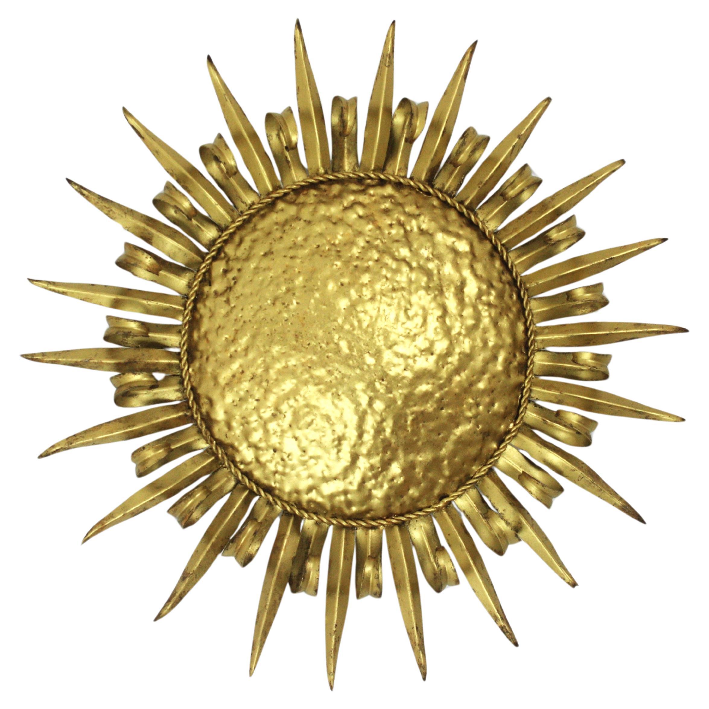 Plafonnier / applique murale en fer doré à cils en forme de soleil, milieu du siècle dernier, années 1950.
Un grand luminaire en fer doré, martelé à la main, avec une alternance de rayons en forme de cils et de rayons droits. Fabriqué à la main en