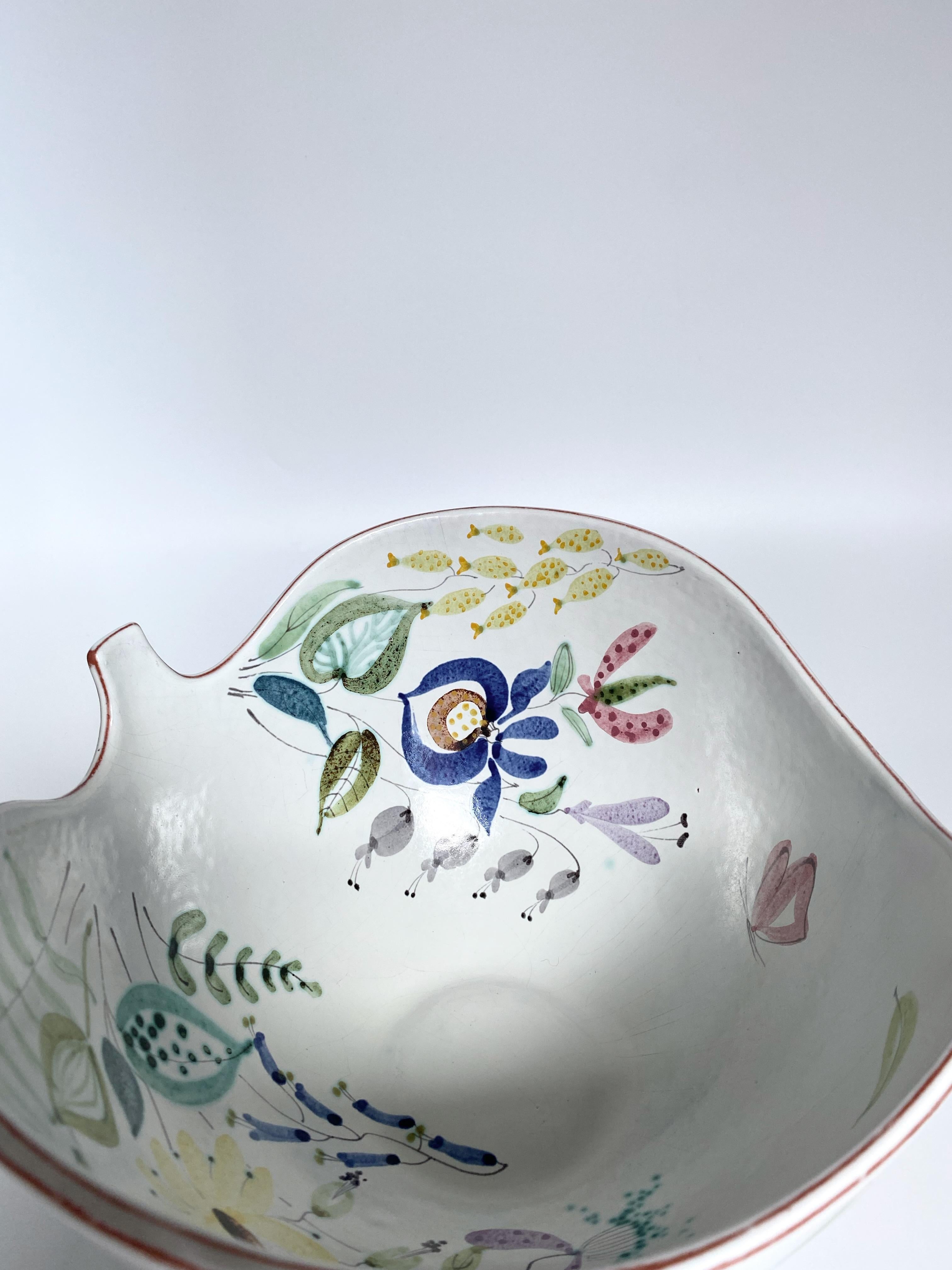 Stunning large Faience ceramic bowl and plate by Stig Lindberg for Gustavsberg. Milky white ceramic featuring a selection of flower motifs in bright colors painted by faience painter Anita Roi after Stig Lindbergs design. In a very good vintage