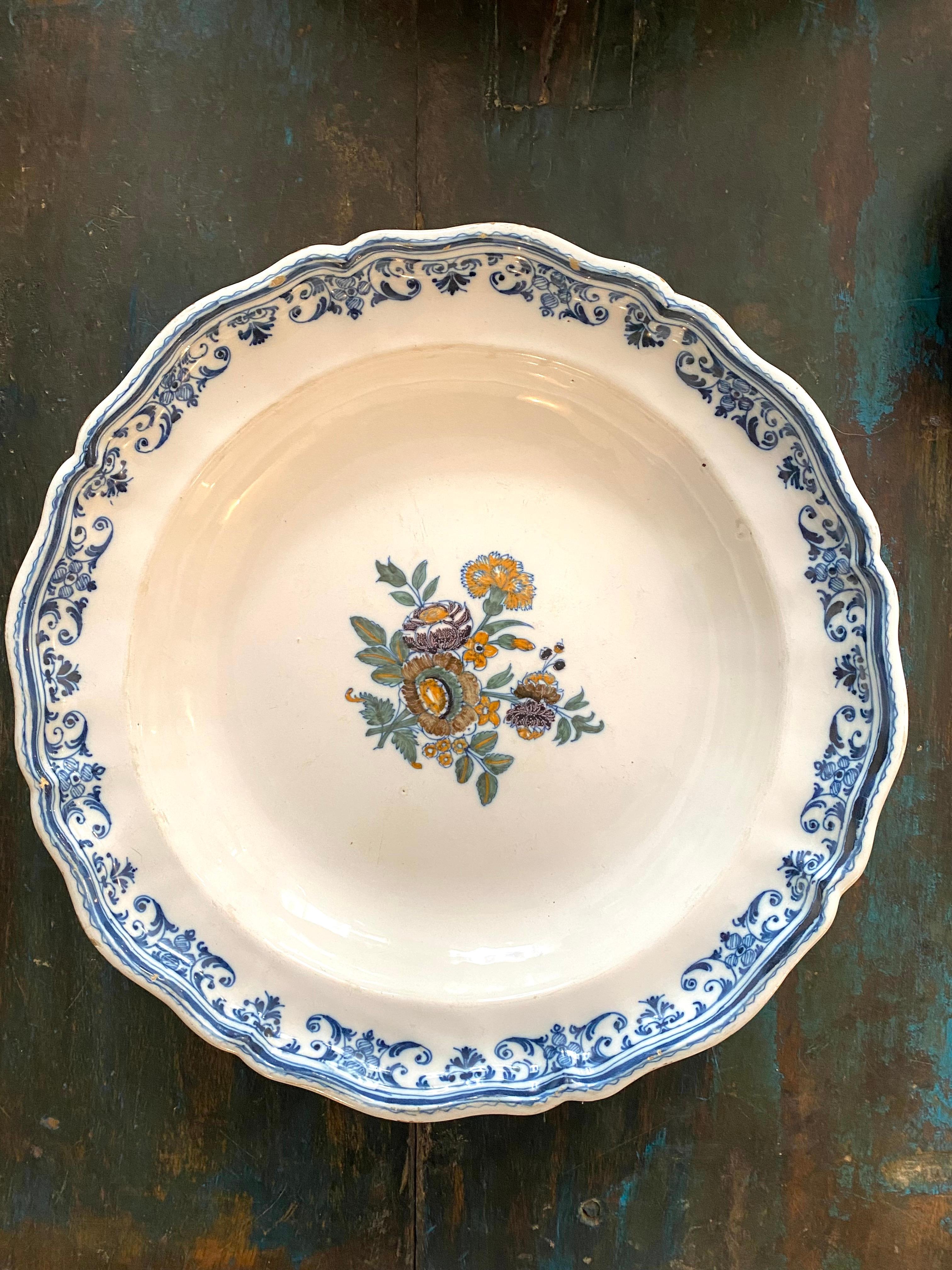 Large 18th century Moustier earthenware dish with polychrome decoration of potato flowers. The scrolled edge is decorated with a frieze with stylized decoration of water leaves. 
Perfect condition