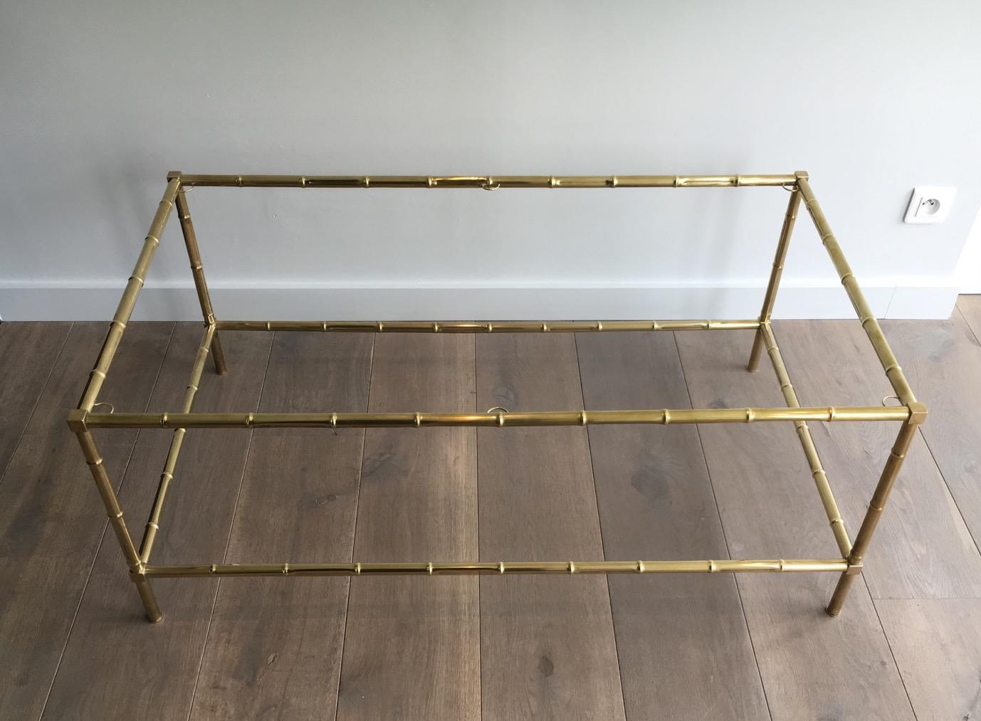 This large faux-bamboo coffee table is all made of brass with a glass shlef on top. This table is a French work in the style of Maison Jansen. Circa 1970.