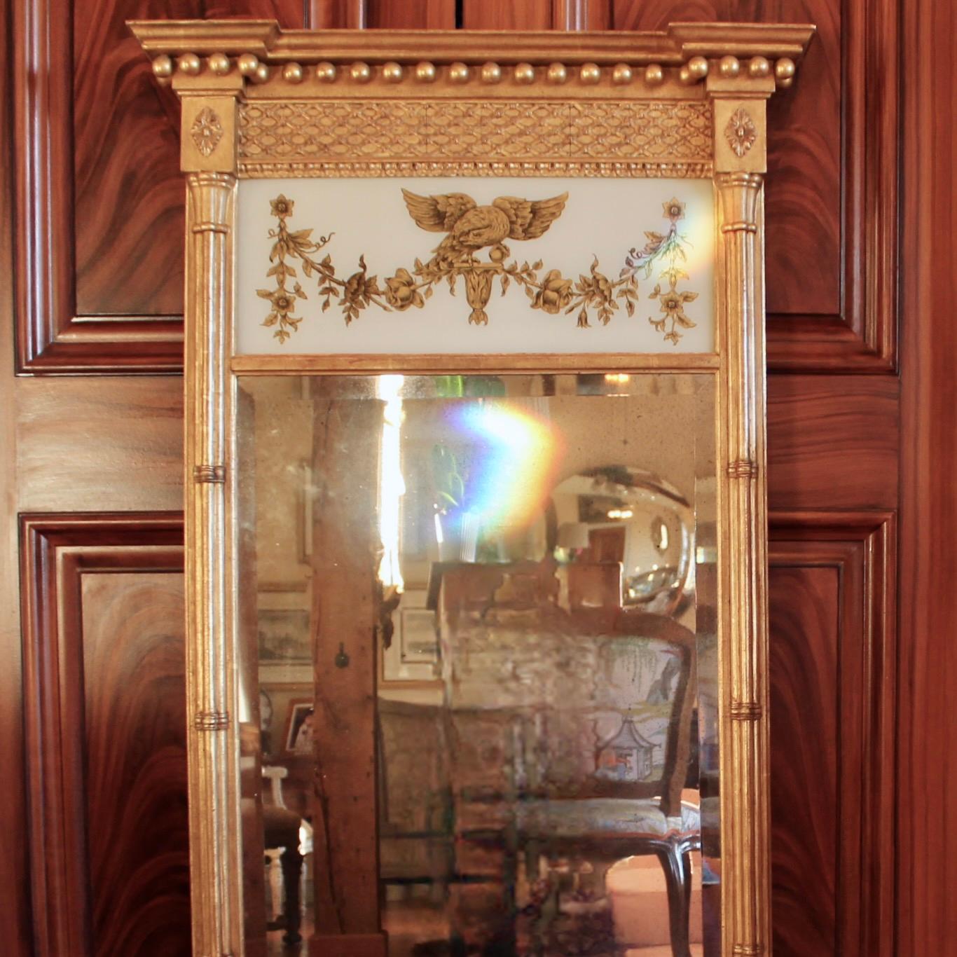 A large and handsome American Federal Style mirror of very good quality in the Federal style, likely made in Italy in the second half of the 20th century. Clusters of colonnettes at the sides support the pediment. An eglomisé panel featuring a