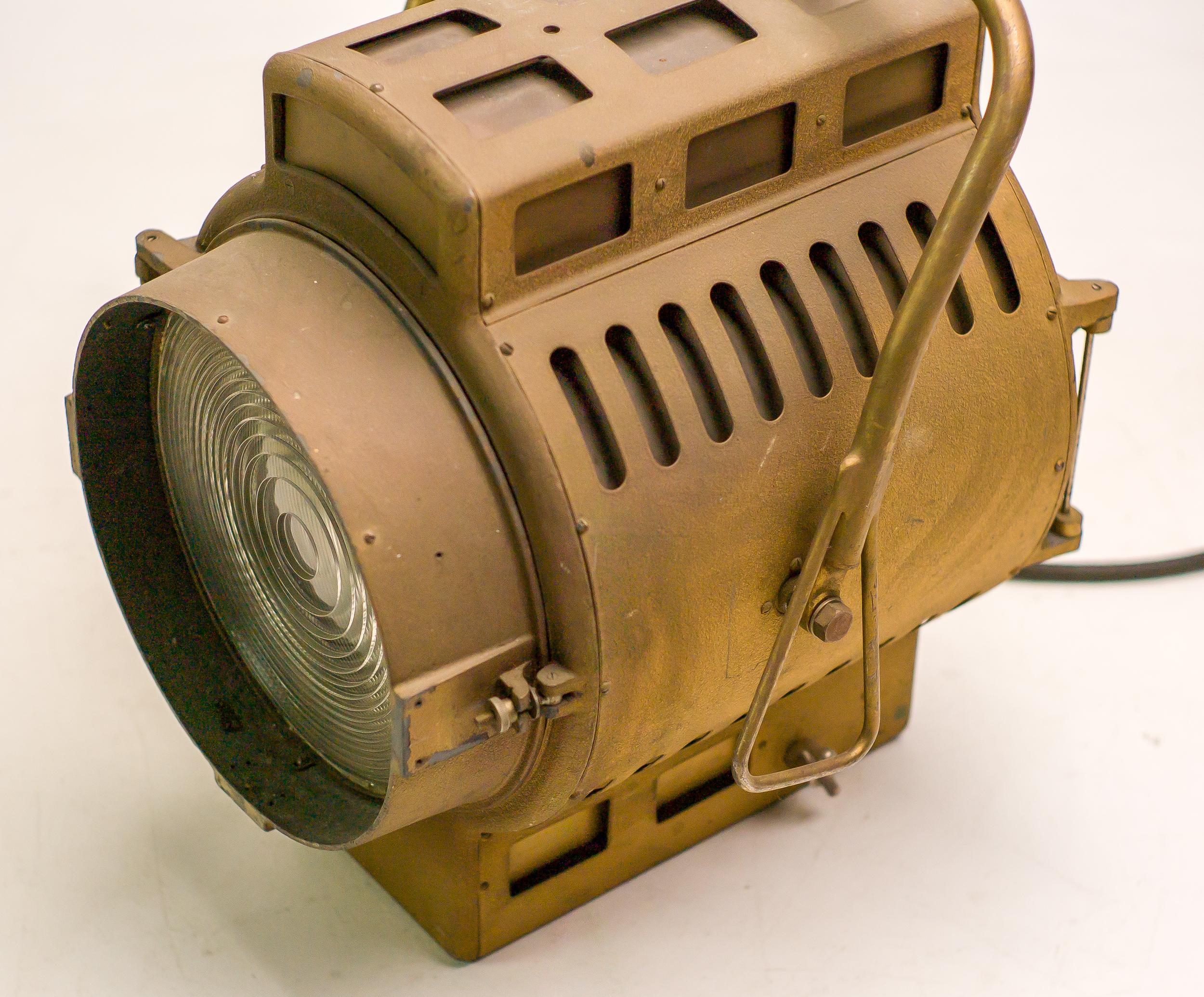 Dieser imposante Scheinwerfer wurde in den 1960er Jahren von Fototon in Ungarn für den Einsatz an professionellen Filmsets hergestellt. Die auf Intensität und Präzision ausgelegte Leuchte verfügt über ein robustes bronzefarbenes Stahlgehäuse mit