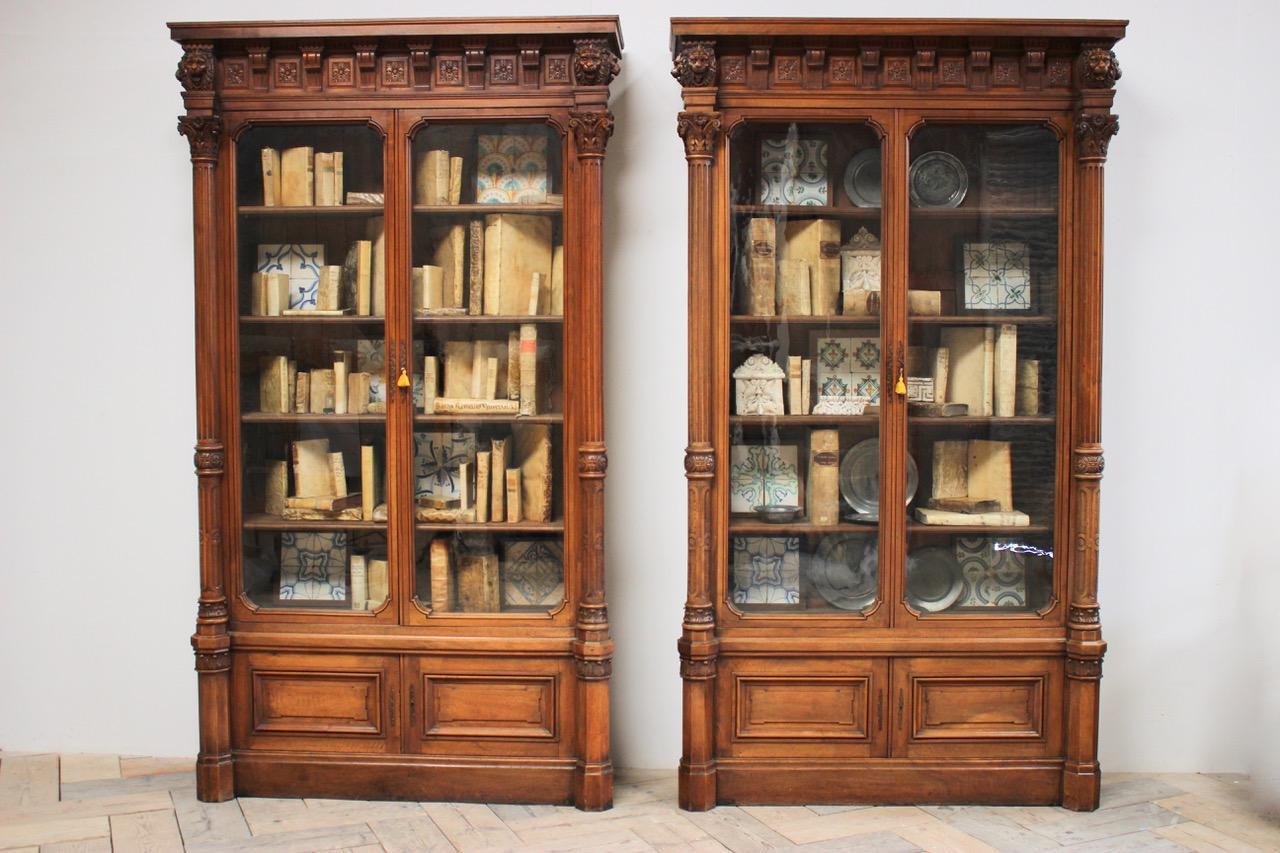 A Grand and impressive pair of 19th century Neoclassical walnut bookcases. 
This superb quality pair of library bookcase cabinets have great proportions and strong Classical Architectural details with bold Dentil frieze and carved Lion mask