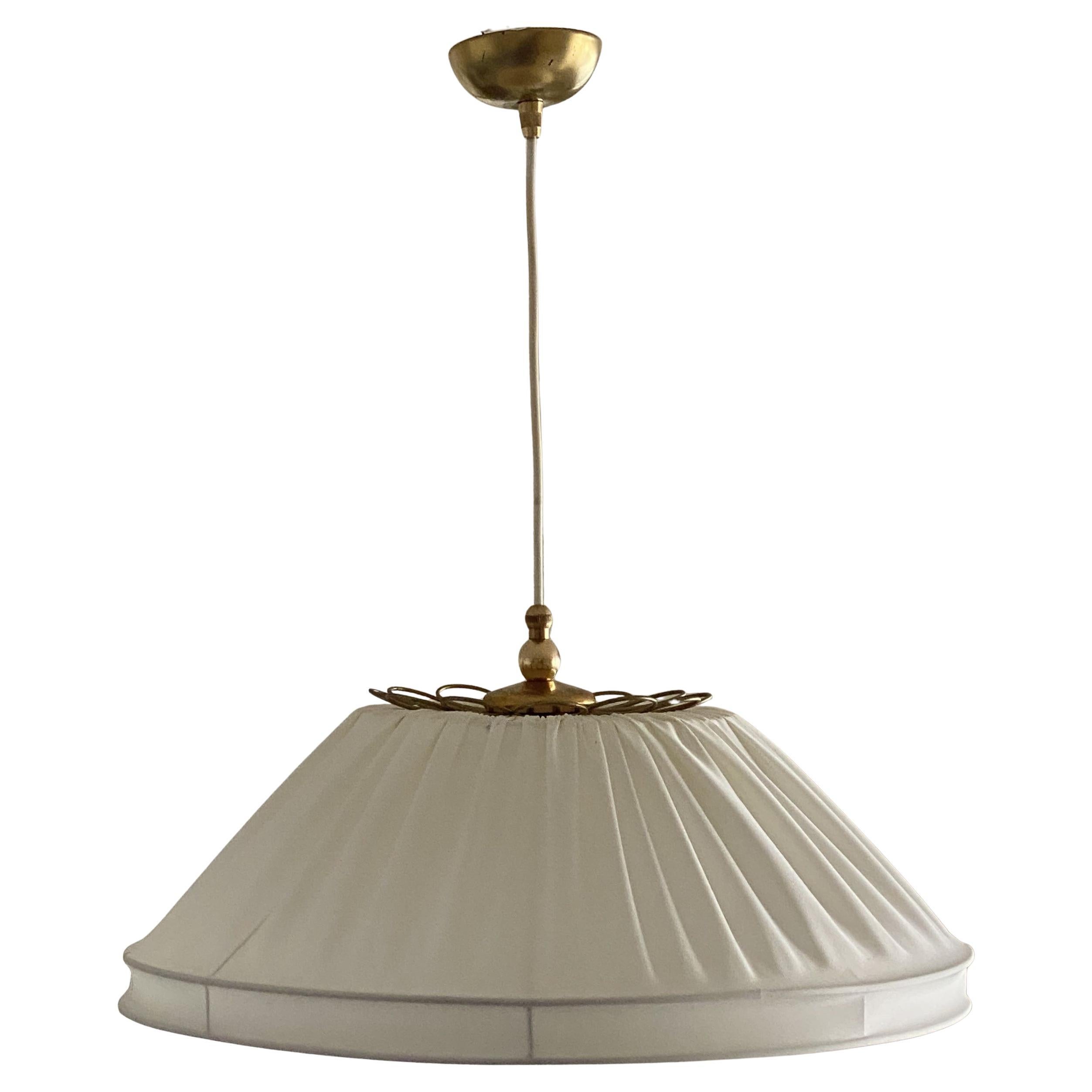 Raro e bellissimo pendente dal design Finish prodotto in Finlandia tra il 1950 e il 1956. Grande paralume in tessuto bianco sporco e montatura in ottone. Questo pendente è dotato di una lampadina con base a vite E27 per una lampadina di grandi