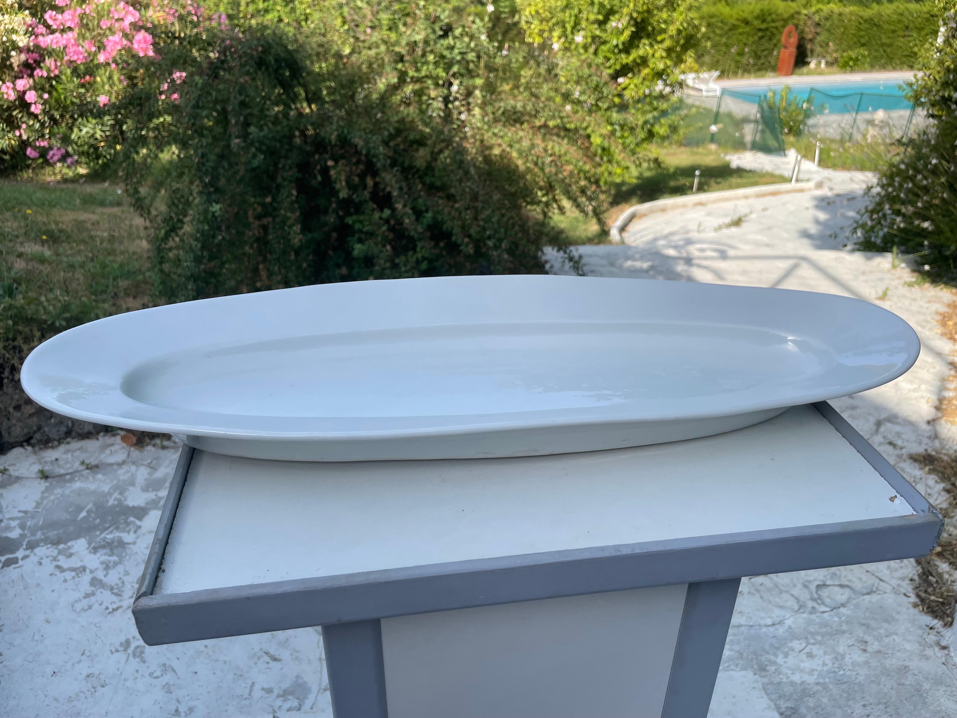It is a white porcelain dish dating from the beginning of the 20th century. It was made in France, and is signed below. It is a dish which is of very good quality, and which is very heavy. It is suitable for serving fish because its shape has a good