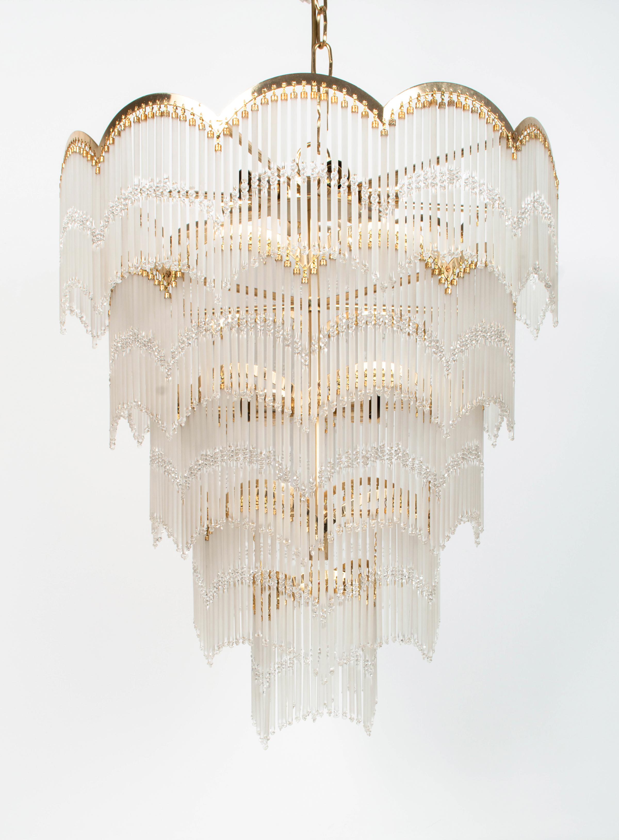 A large five tier waterfall chandelier, England C.1970

The gilt frame hung with five tiers of frosted glass cylinders. 
Eleven bulb.

Measures: Body: 70cm high x 60cm diameter

Chain Additional 32cm in height.

A stunning statement piece, in