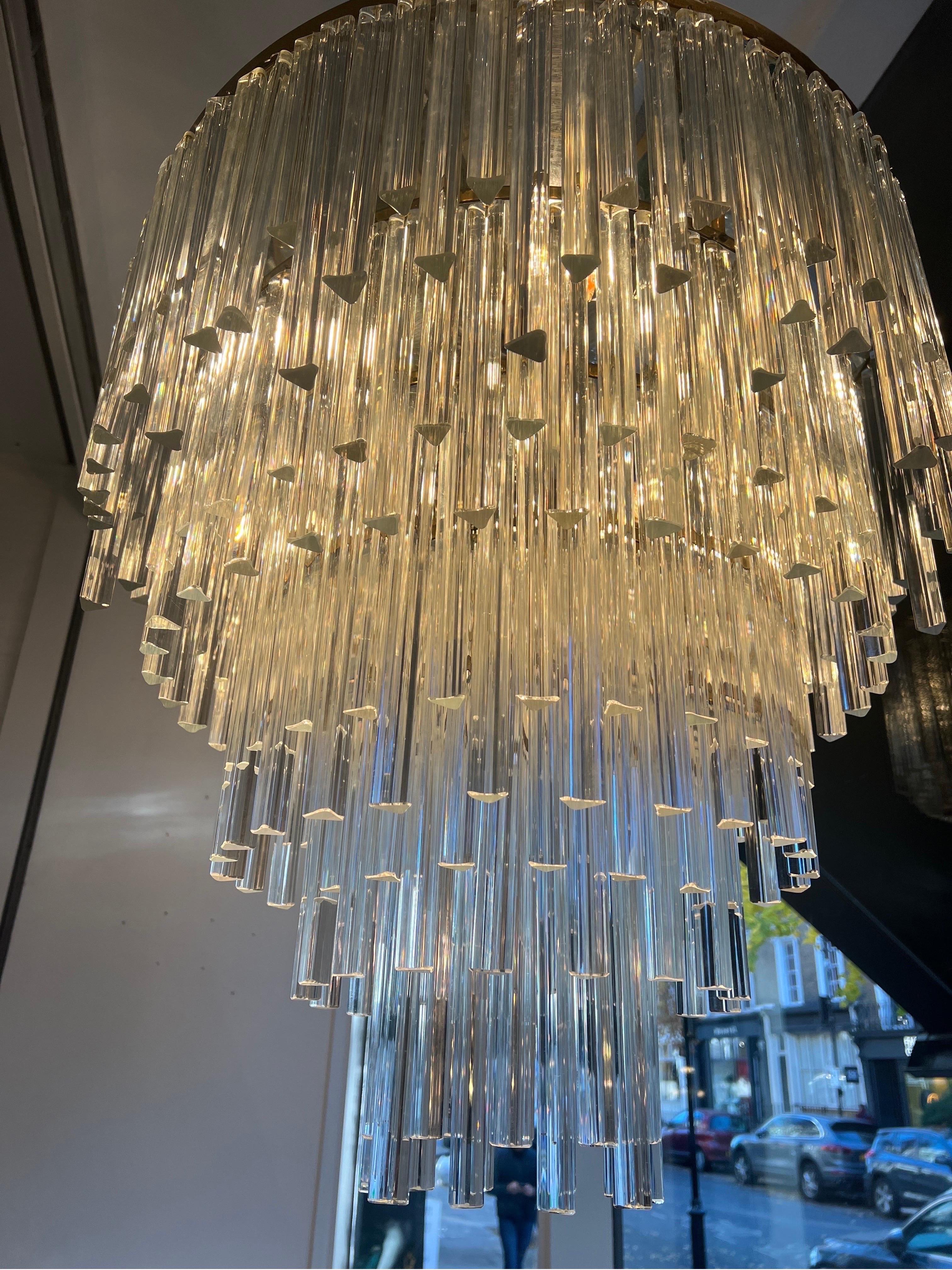 Un remarquable lustre en cascade à cinq niveaux composé de 300 verres de Murano taillés à la main en trois tailles différentes. La structure est en laiton avec une plaque en miroir au sommet permettant à la lumière de se refléter progressivement sur