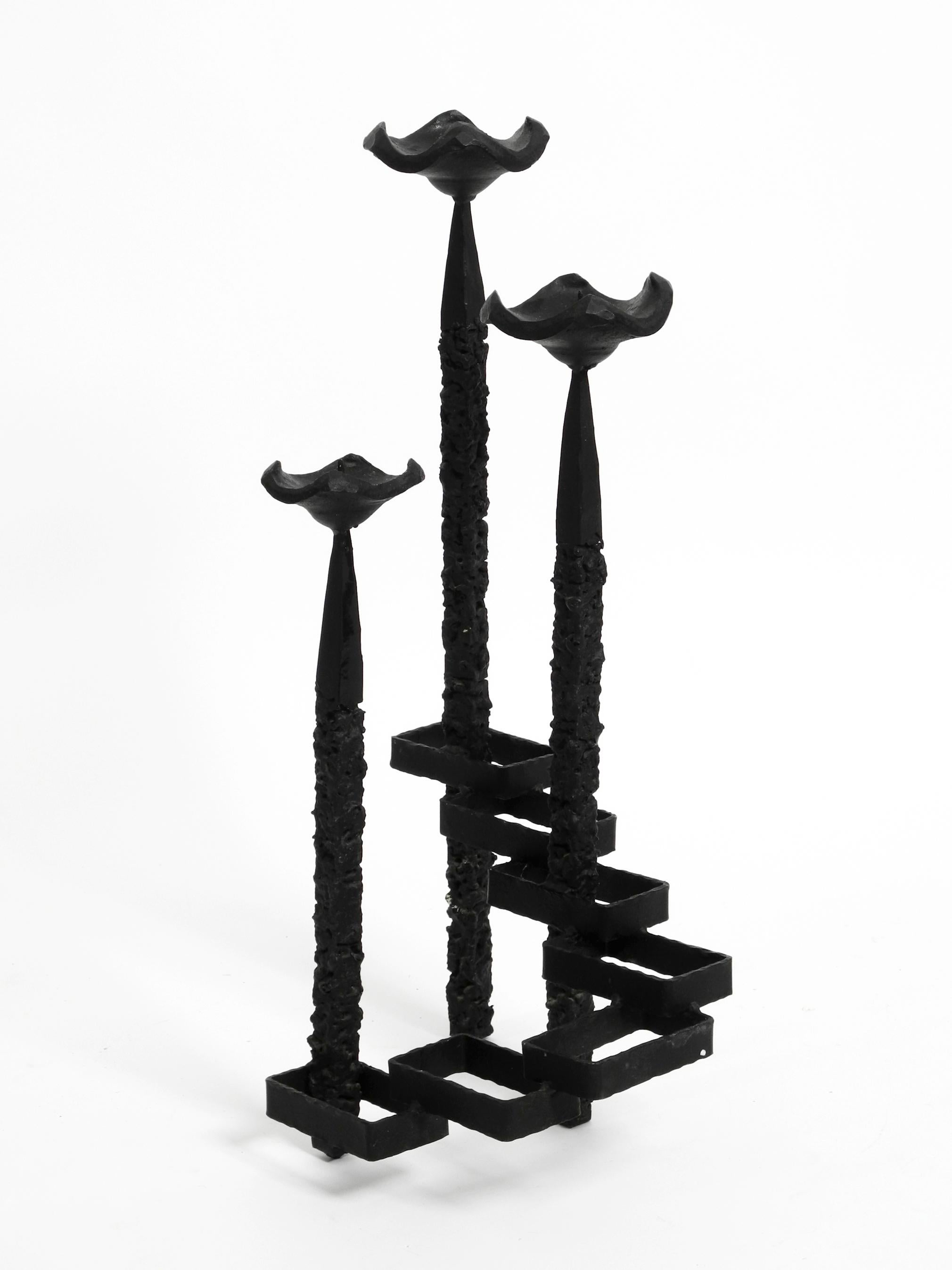 Extraordinary large floor or table candle holder made of wrought iron in abstract Brutalist design. 
For three candles.
The great, very high-quality design piece is 60 cm high without candles and weighs approx. 8 kg.
Very stable hold without