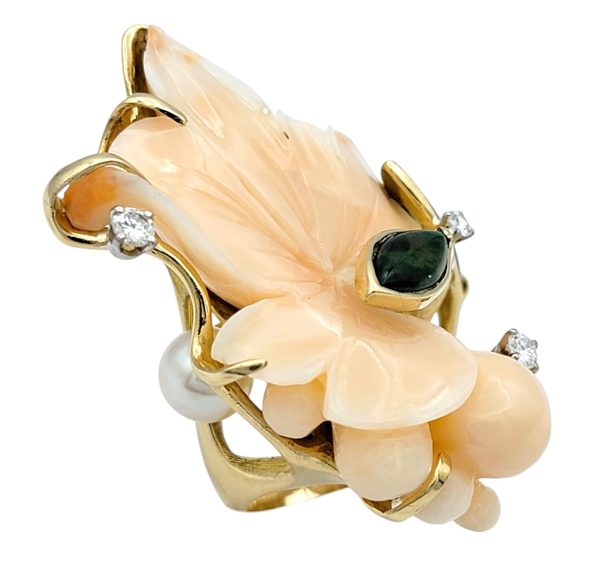 Ring Size: 5.75

Step into a world of magnificent artistry and elegance with this extraordinary gemstone cocktail ring. This unique masterpiece is a celebration of nature’s finest treasures, blending the soft peachy hues of carved coral with the