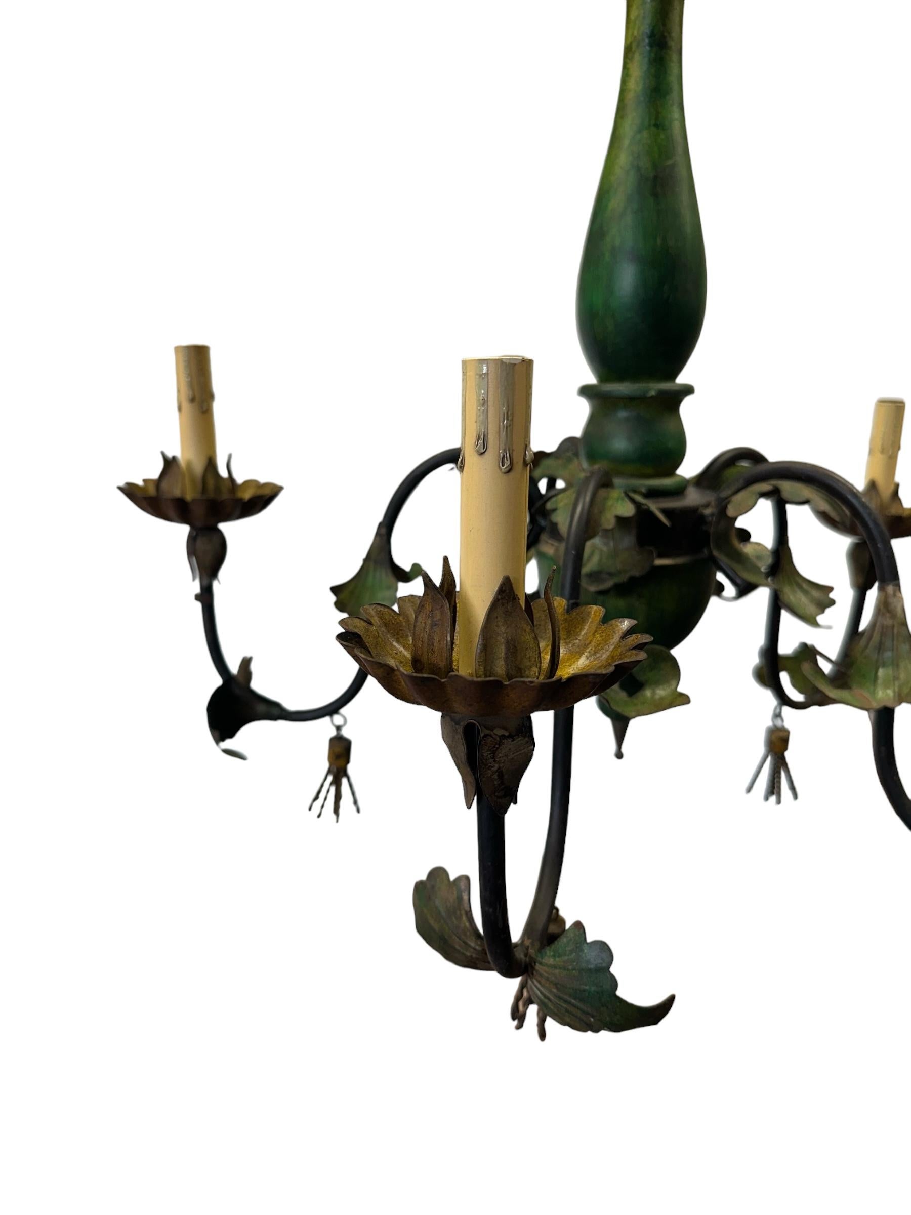 Presenting a unique and wonderful, large Italian wood and tole chandelier featuring scrollwork and tassels. Predominately green with large metal arms, white candelabra and lovely accents. Loads of rustic charm for your entryway or dining