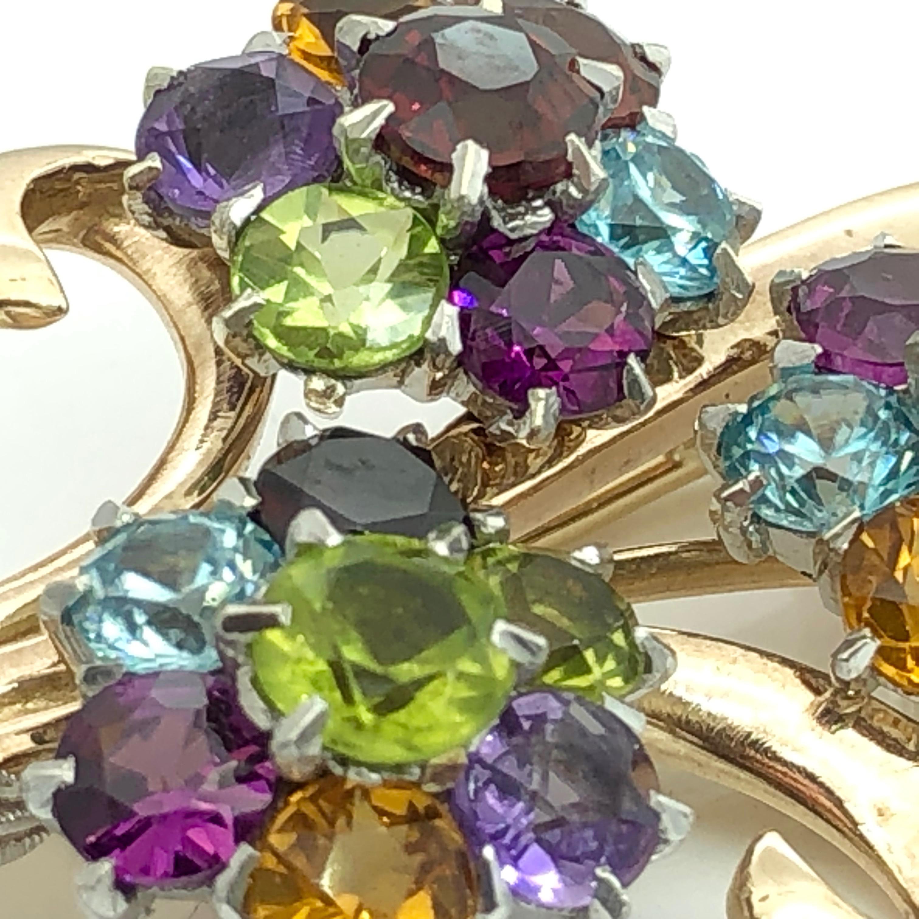 Large luxurious flower bouquet pin brooch
Set in 9 carat yellow gold, stamped 375 and inscribed DJE
Twenty one multicoloured semi-precious stones - Peridots, Aquamarines, Citrines, Garnets, Amethysts
Ribbon in white gold set with rose cut