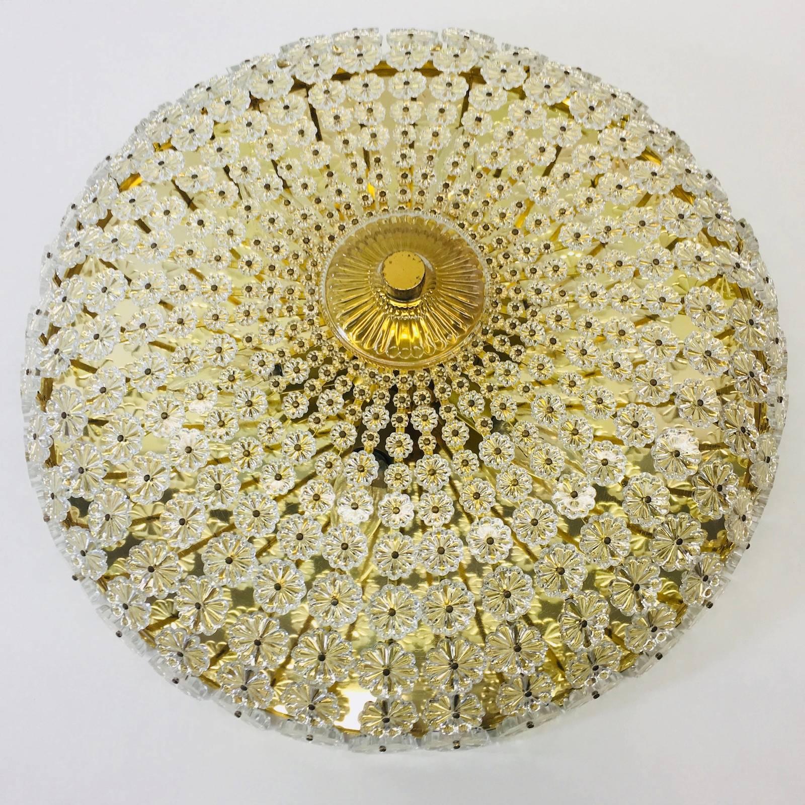 Large flower shaped flush mount designed by Emil Stejnar in the 1960s in Austria. It features a brass frame with hundreds of lovely crystal glass pieces designed to portray the image of a spectacular flower surrounding the frame. This flush mount
