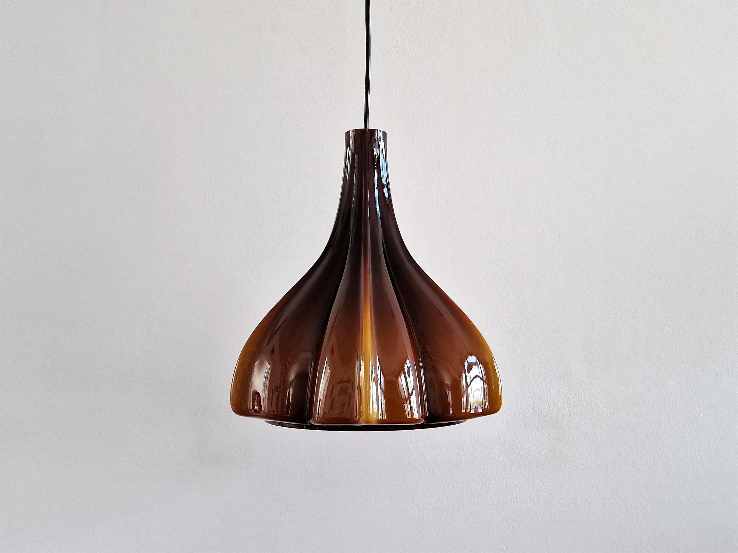 This beautiful flower shaped pendant lamp was made by the German manufacturer Peill & Putzler. It is made of double-layerd hand blown Murano glass with a brown outside and an opal white inside. When lit it creates a warm and atmospheric glow of