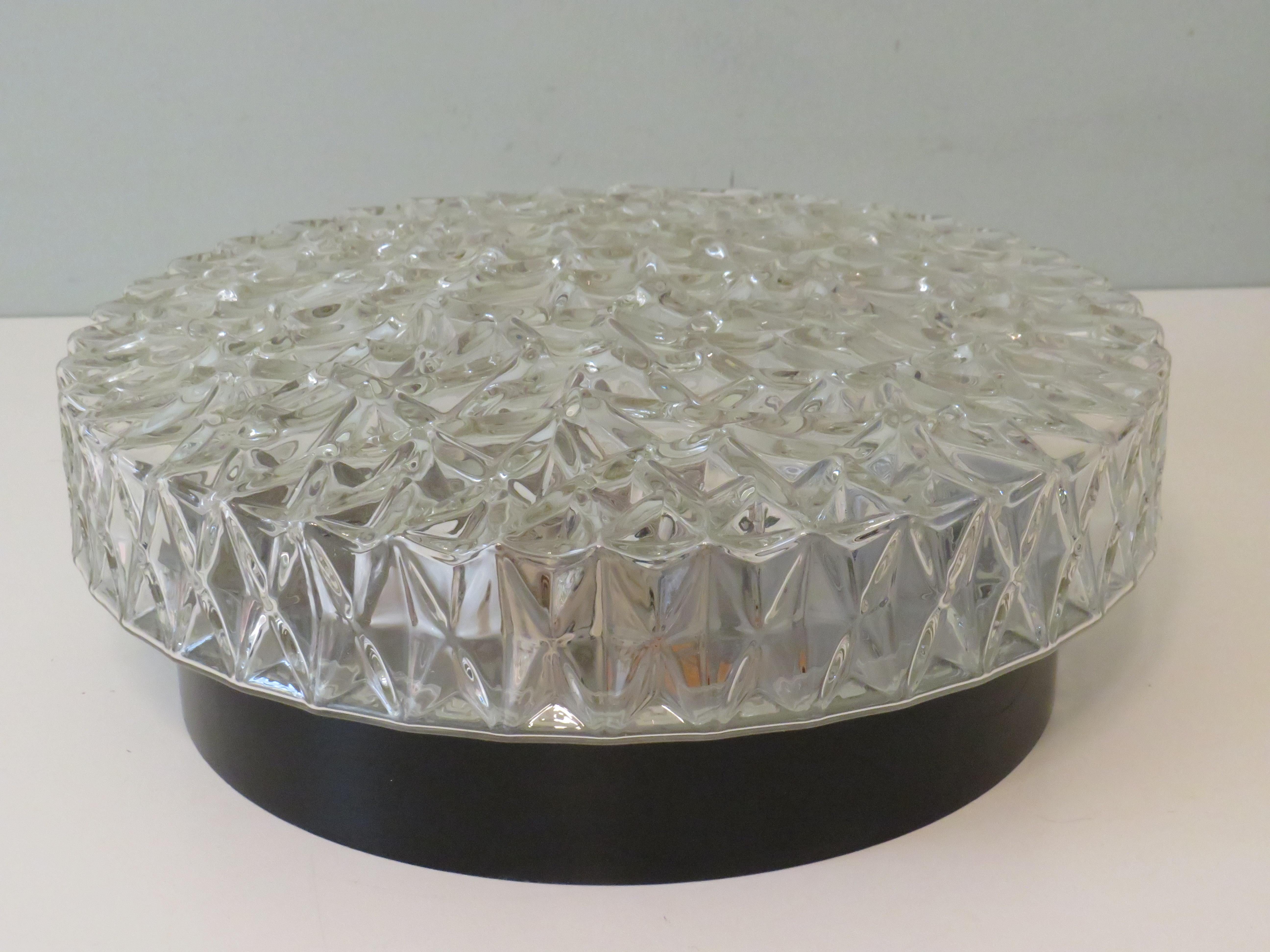Round heavy ceiling lamp with black metal ceiling or wall mounting plate and 2 porcelain sockets E 27.
The glass dome has geometric motifs that create a beautiful light effect.
The diameter of the lamp is 30 cm and the height is 11 cm.
The lamp