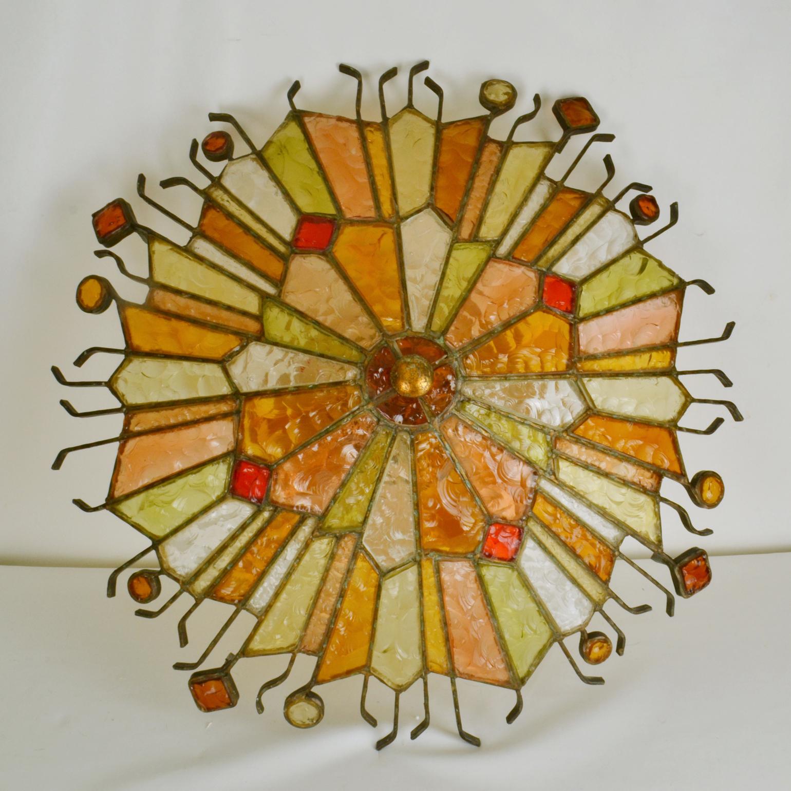 Large flush mount ceiling lamp by Poliarte in Verona, Italy, circa 1975. The lamp radiates in geometric segments of alternating translucent and colored hand chipped glass creating a circular relief to break the light, in amber, red, orange, peach